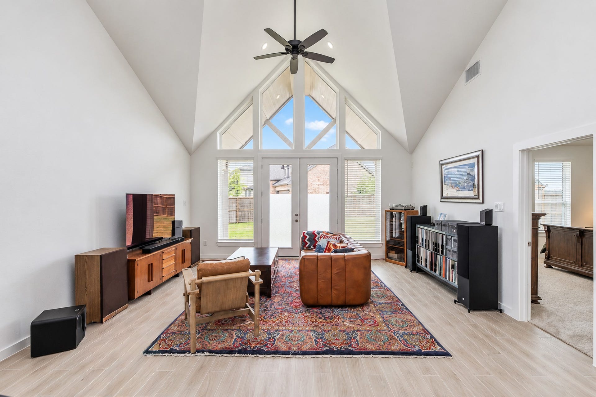16922 Warm Glow Court, Hockley, TX 77447 Spacious living room with soaring vaulted ceilings, abundant natural light from large windows, and stylish hardwood floors, creating a warm and inviting atmosphere.