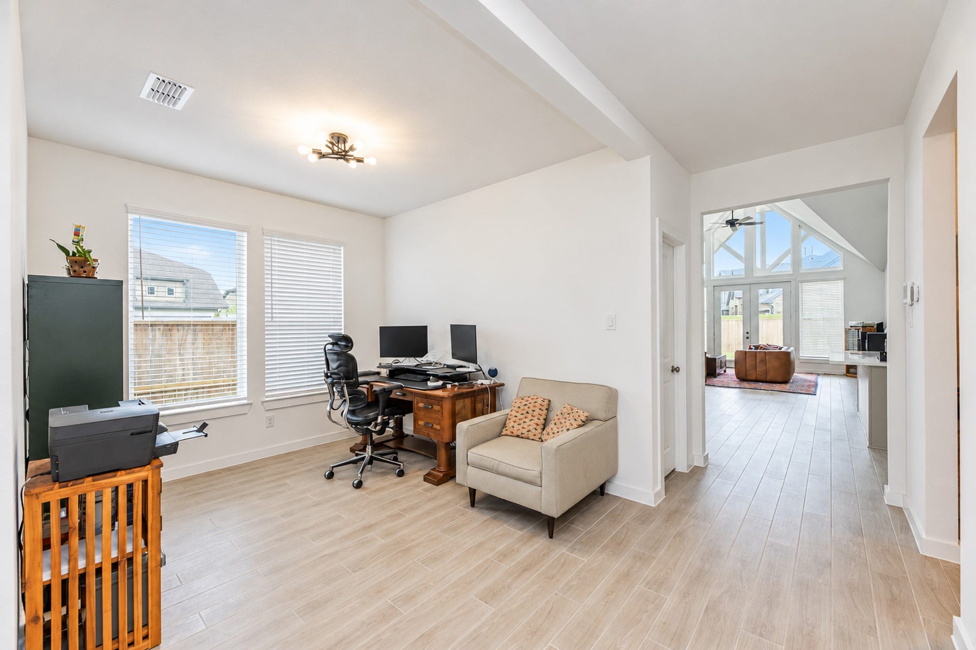 16922 Warm Glow Court, Hockley, TX 77447 Bright and inviting home office with elegant wood flooring, ample natural light from large windows, and an open view leading into a spacious living area with vaulted ceilings.