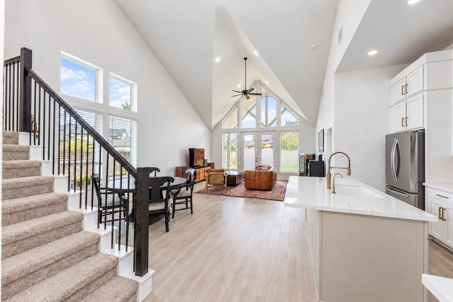 16922 Warm Glow Court, Hockley, TX 77447 Stunning open-concept living area with soaring vaulted ceilings, large windows for natural light, and modern finishes. The kitchen features sleek countertops and stainless steel appliances, seamlessly flowing into a cozy seating area and dining space.
