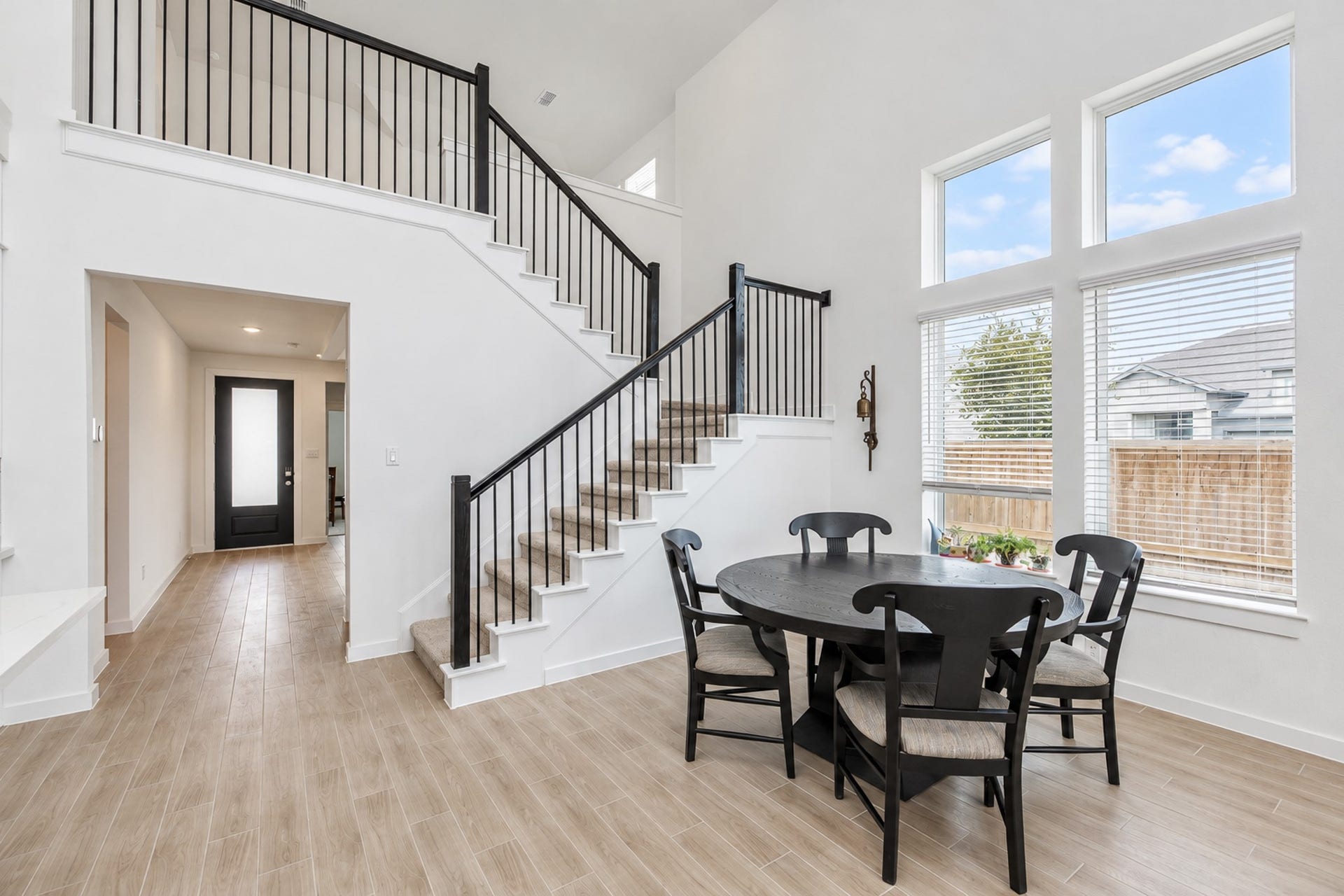16922 Warm Glow Court, Hockley, TX 77447 Bright and airy dining area with large windows and high ceilings, featuring a modern staircase and open layout.