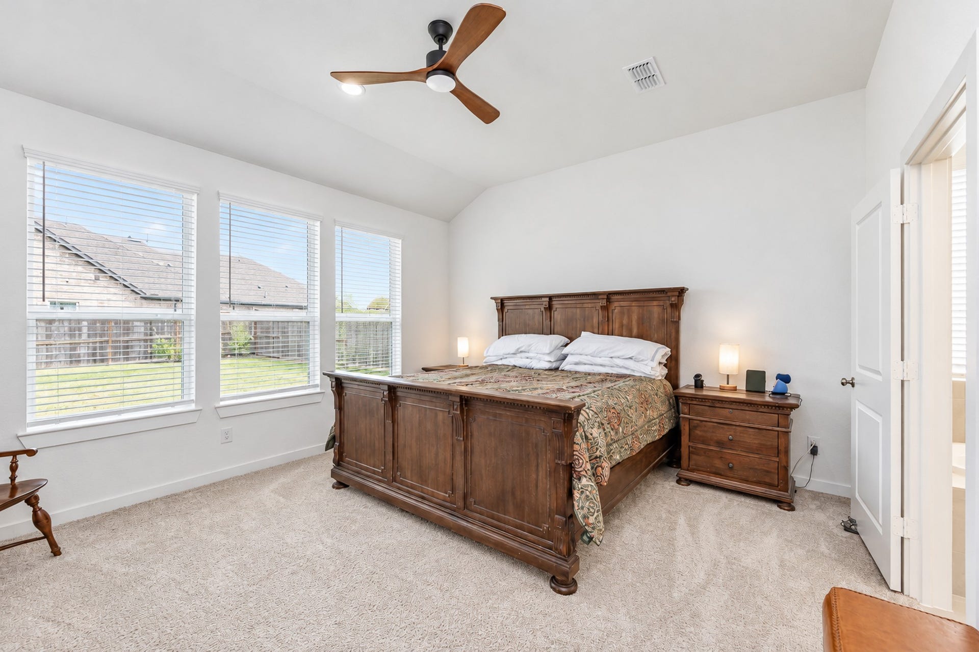 16922 Warm Glow Court, Hockley, TX 77447 Spacious bedroom with vaulted ceiling, featuring abundant natural light from large windows, and a cozy atmosphere with a classic wooden bed and matching nightstand.