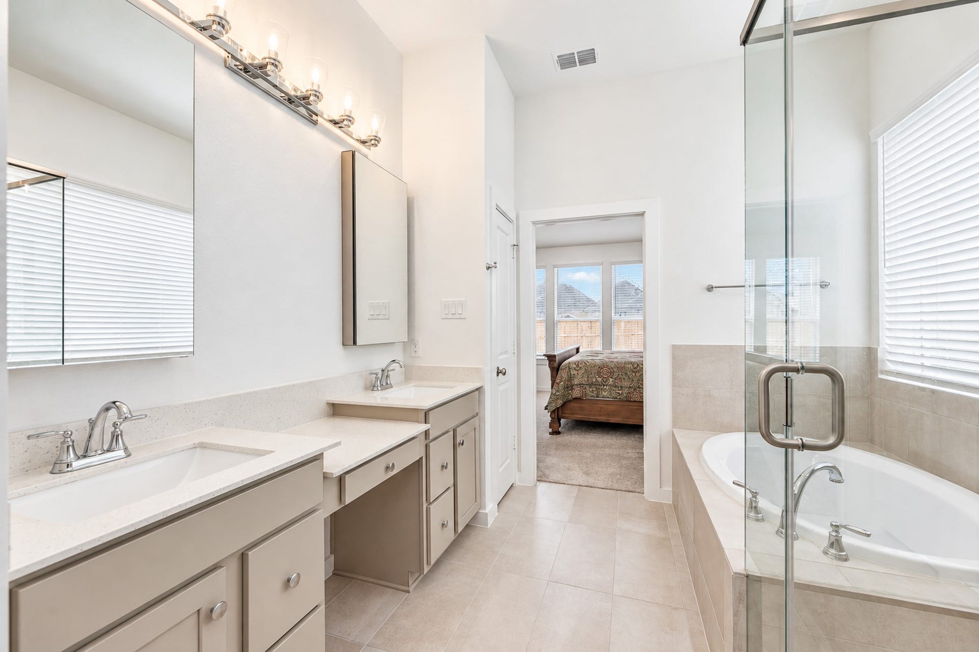 16922 Warm Glow Court, Hockley, TX 77447 Bright and spacious bathroom featuring dual sinks, ample cabinetry, a luxurious soaking tub, and a glass-enclosed shower, seamlessly connecting to the bedroom.