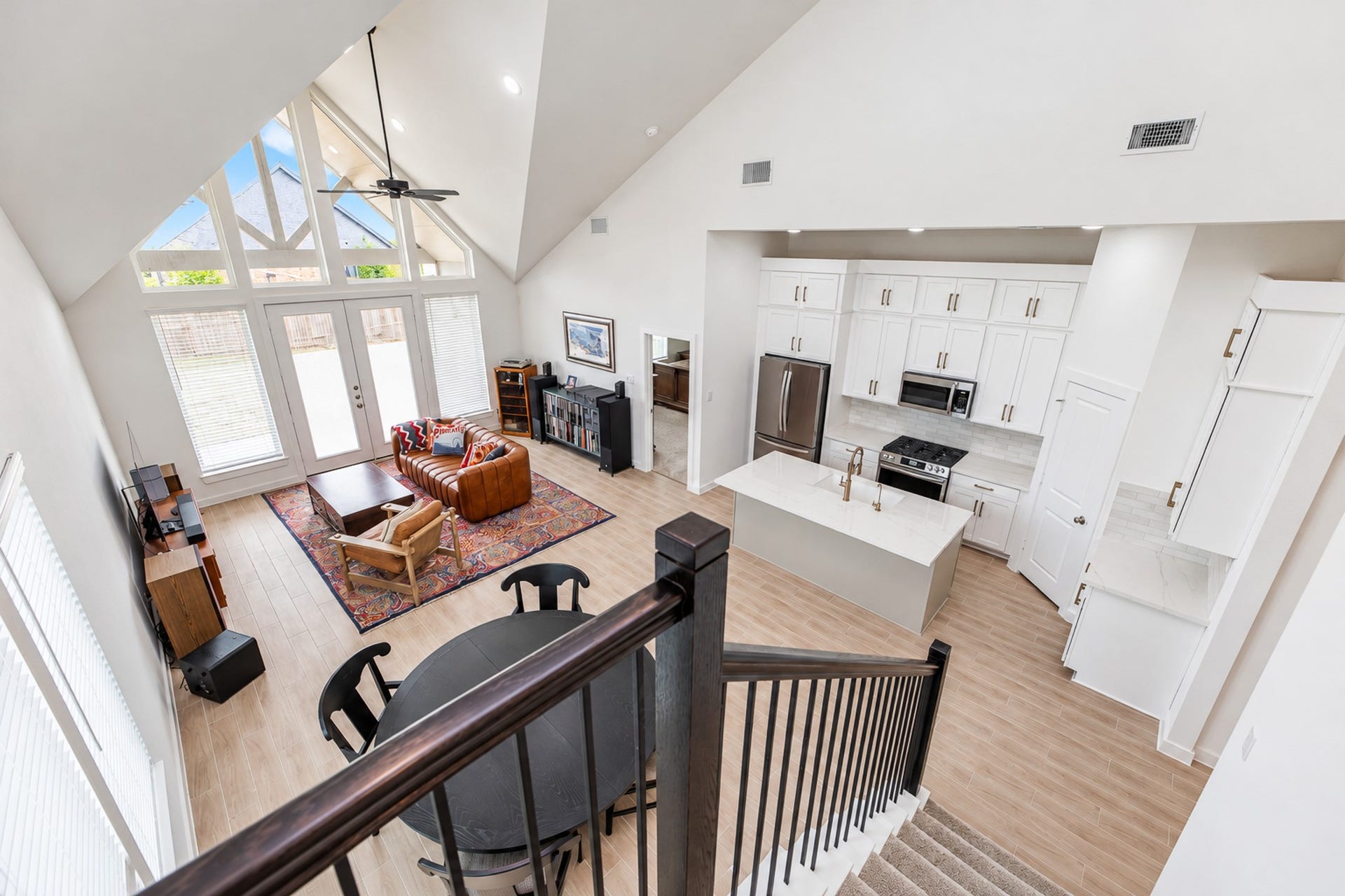 16922 Warm Glow Court, Hockley, TX 77447 Stunning open-concept living space with soaring vaulted ceilings, abundant natural light from large windows, and a modern kitchen featuring sleek cabinetry and stainless steel appliances.