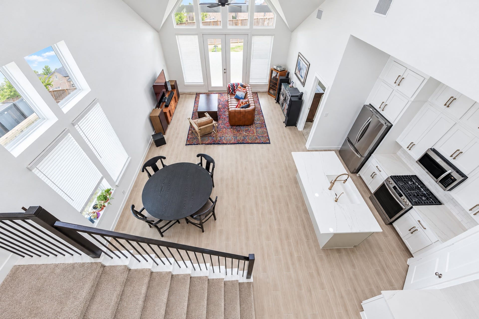 16922 Warm Glow Court, Hockley, TX 77447 Spacious and bright open-concept living area with soaring ceilings, modern kitchen featuring stainless steel appliances, and abundant natural light from large windows.