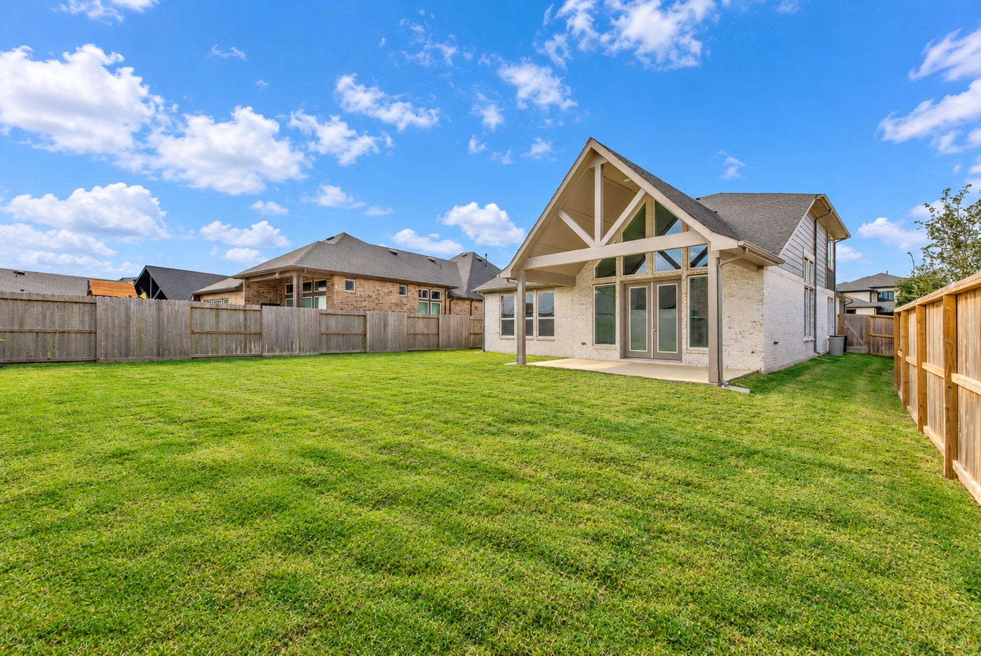16922 Warm Glow Court, Hockley, TX 77447 Spacious backyard with lush green lawn, perfect for outdoor activities, featuring a charming covered patio and modern architectural details.