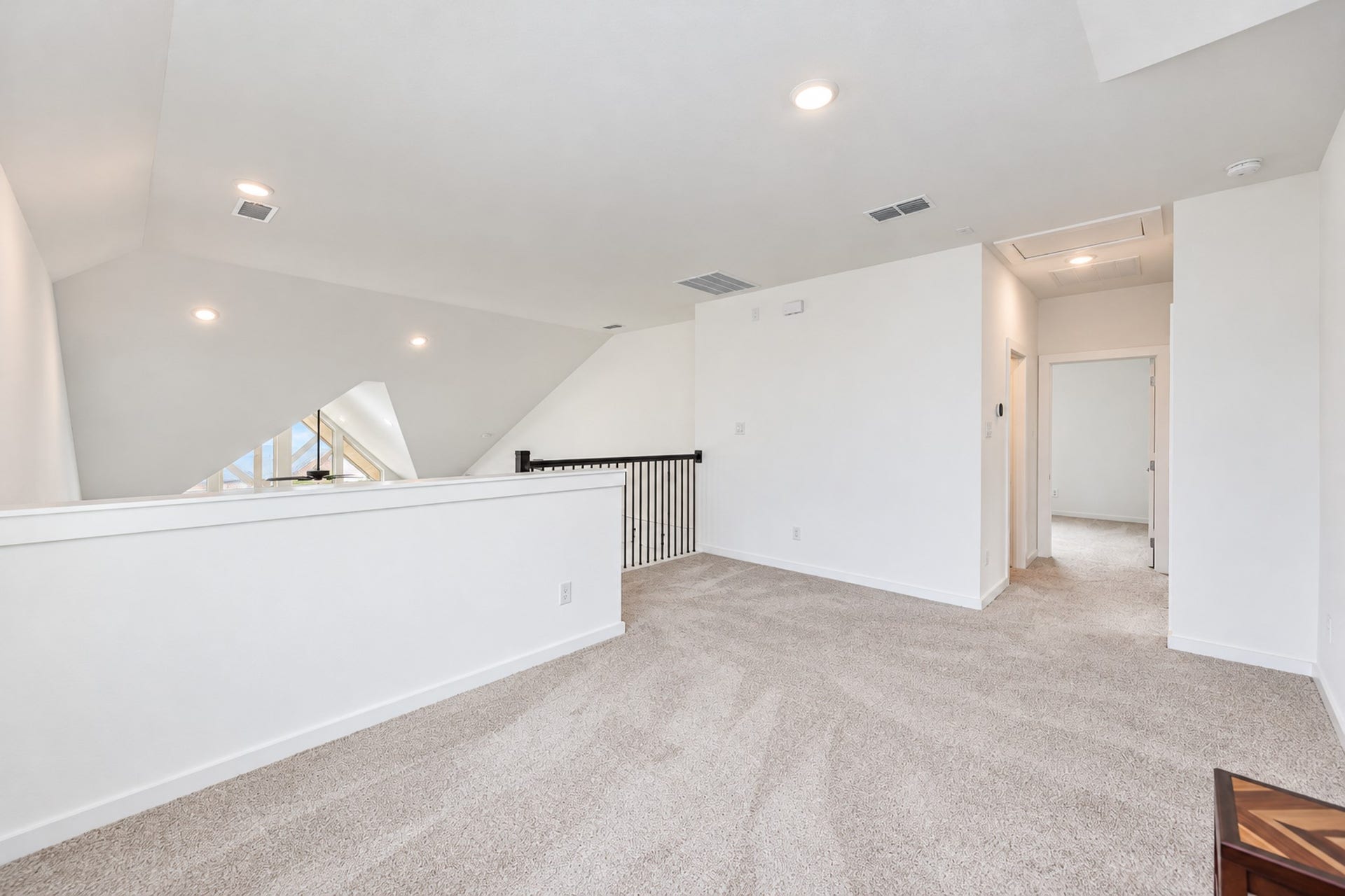 16922 Warm Glow Court, Hockley, TX 77447 Spacious upper-level landing with plush carpeting and recessed lighting, offering access to additional rooms and featuring a modern railing detail.