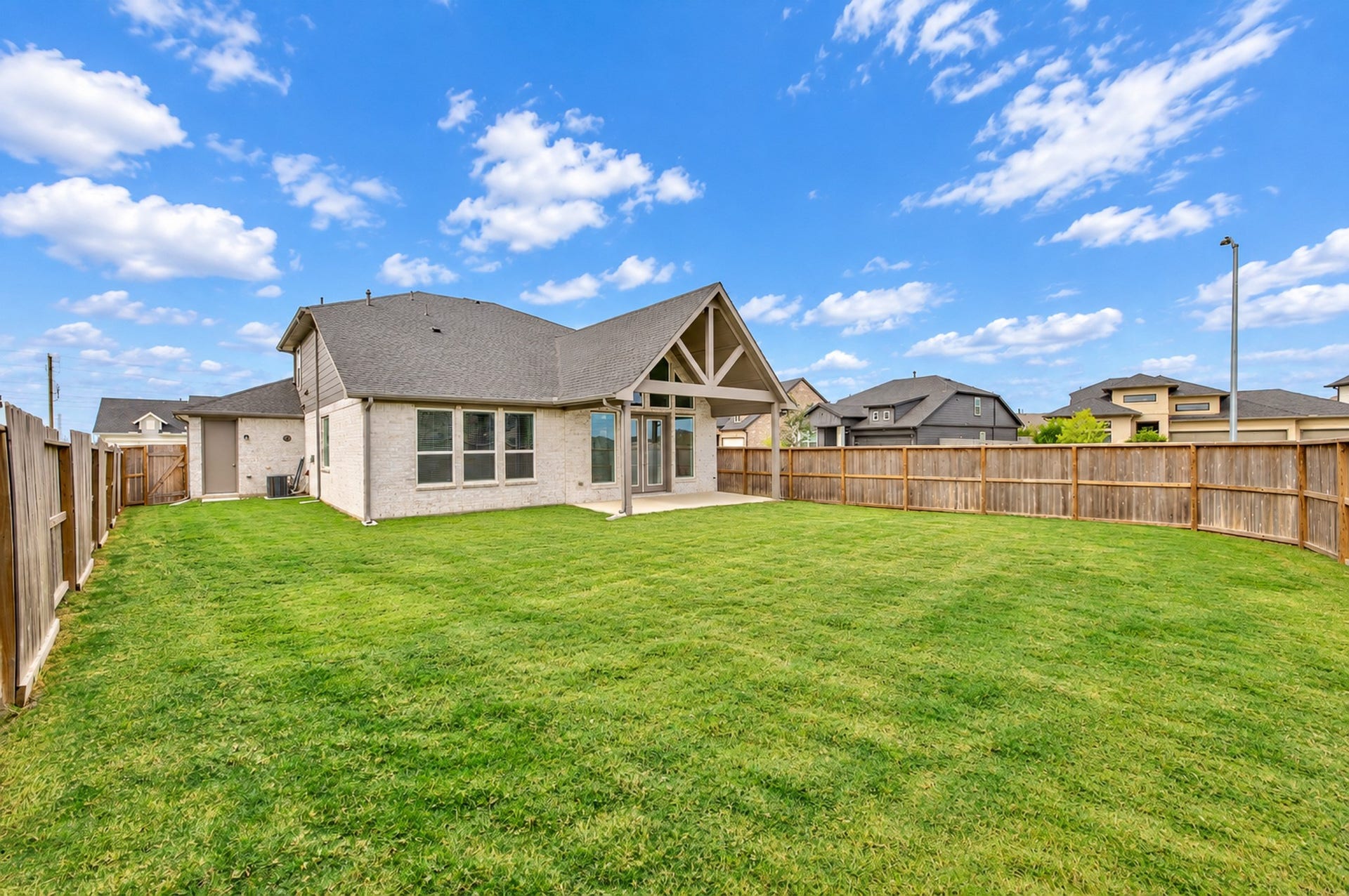 16922 Warm Glow Court, Hockley, TX 77447 Spacious backyard with a lush green lawn, perfect for outdoor activities, surrounded by a wooden fence for privacy.