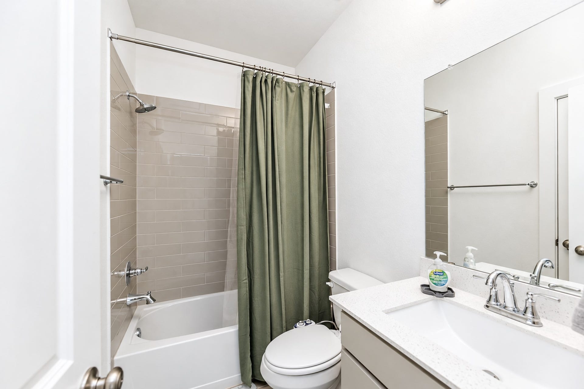 16922 Warm Glow Court, Hockley, TX 77447 Bright and modern bathroom featuring a sleek vanity with a polished countertop, a full bathtub with a tiled shower, and a contemporary shower curtain for added privacy.