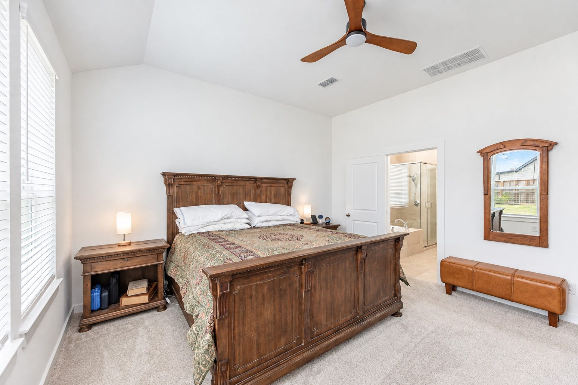 16922 Warm Glow Court, Hockley, TX 77447 Spacious bedroom with a vaulted ceiling, natural light, and a classic wood bed set, leading to an en-suite bathroom.
