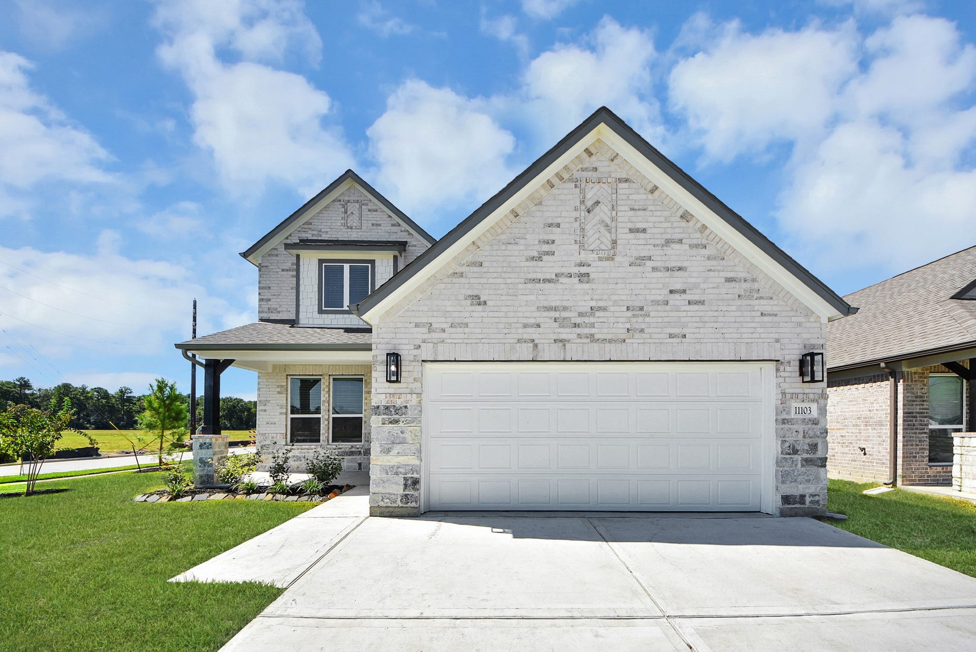 11103 Tulip Ridge Trail, Houston, TX 77044 Meticulously maintained yard and lush landscape, paired with a premium elevation featuring captivating brick accents. Modern coach lights add a touch of contemporary elegance to the exterior.