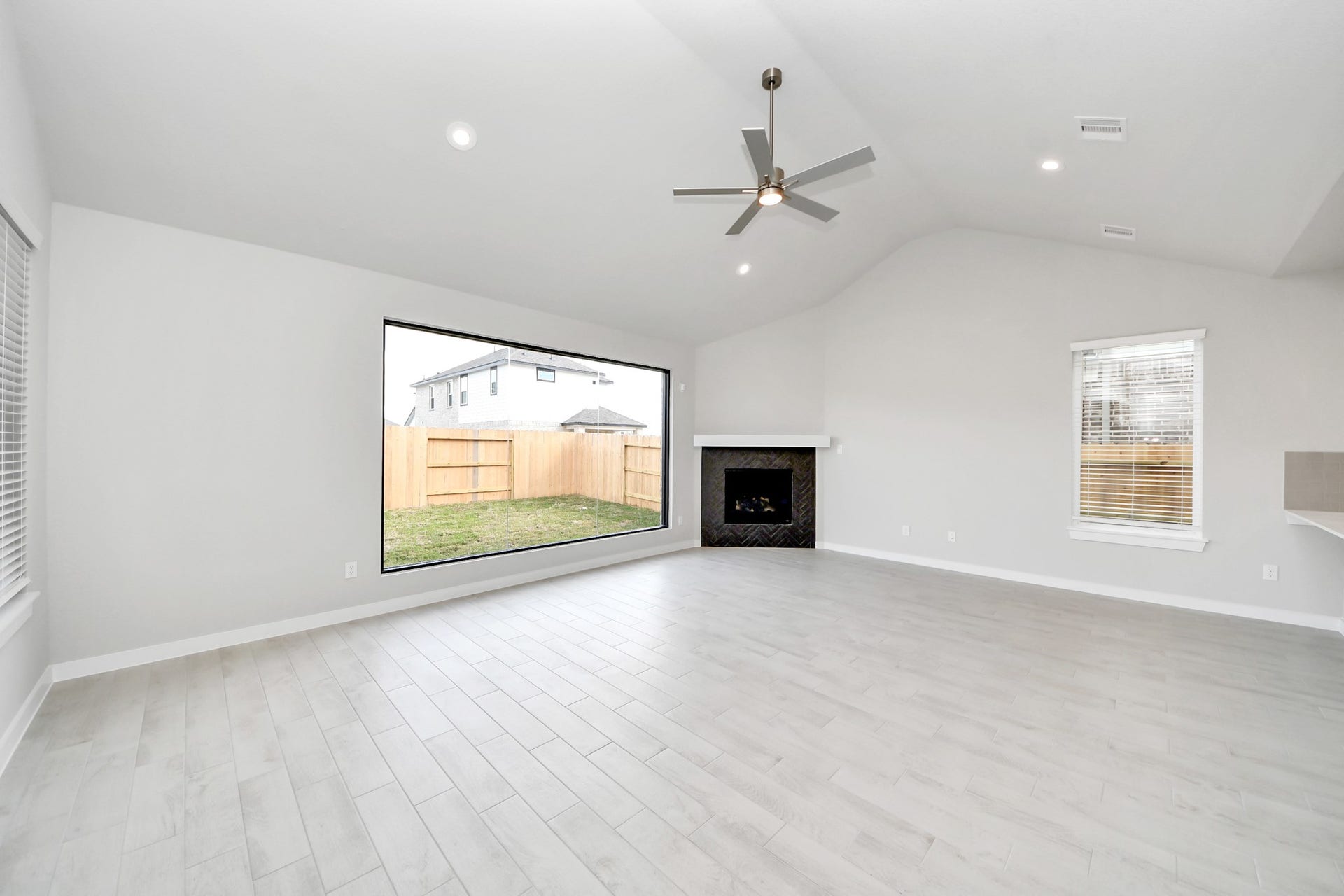 11103 Tulip Ridge Trail, Houston, TX 77044 Family room flooded with natural light through the expansive windows. The premium tile flooring adds a touch of luxury to the space, creating the perfect setting for relaxing moments and cherished gatherings with loved ones. Sample photo of completed home with similar floor plan. Actual colors and selections may vary.