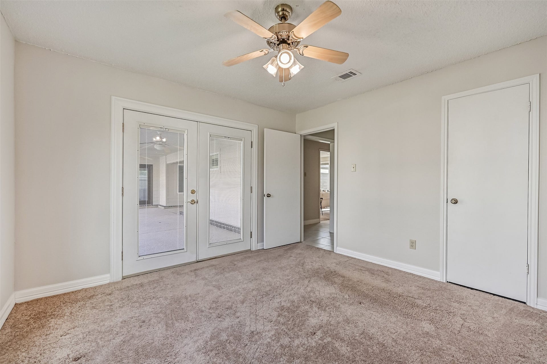 French doors in this secondary bedroom open directly to the covered backyard patio, offering convenient access to the swimming pool. Neutral finishes, carpeting & a ceiling fan make this a flexible space for guests, a home office or additional bedroom, with a closet for storage.