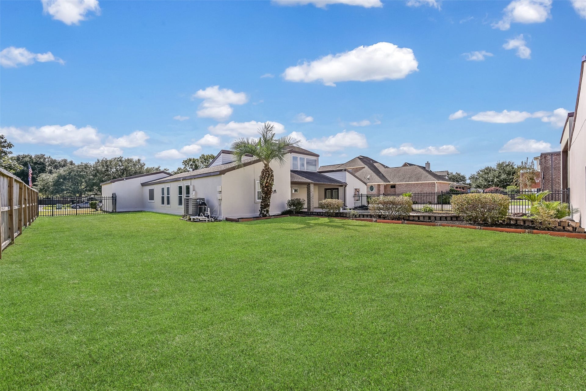 A generous grassy backyard offers additional outdoor space beyond the swimming pool and covered patio. Mature landscaping, a palm tree & fenced boundaries complement the setting, while the home's distinctive architecture and adjoining aviation facilities make this property truly unique.