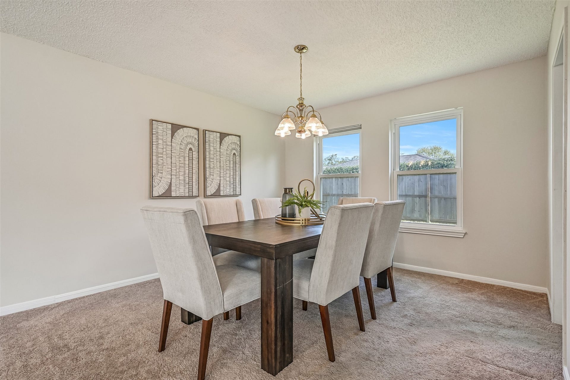 The formal dining room offers a comfortable setting for gatherings, with soft neutral carpeting, a traditional chandelier & two windows overlooking the backyard. Conveniently positioned beside the kitchen, this dedicated dining space easily accommodates a full-size dining table.