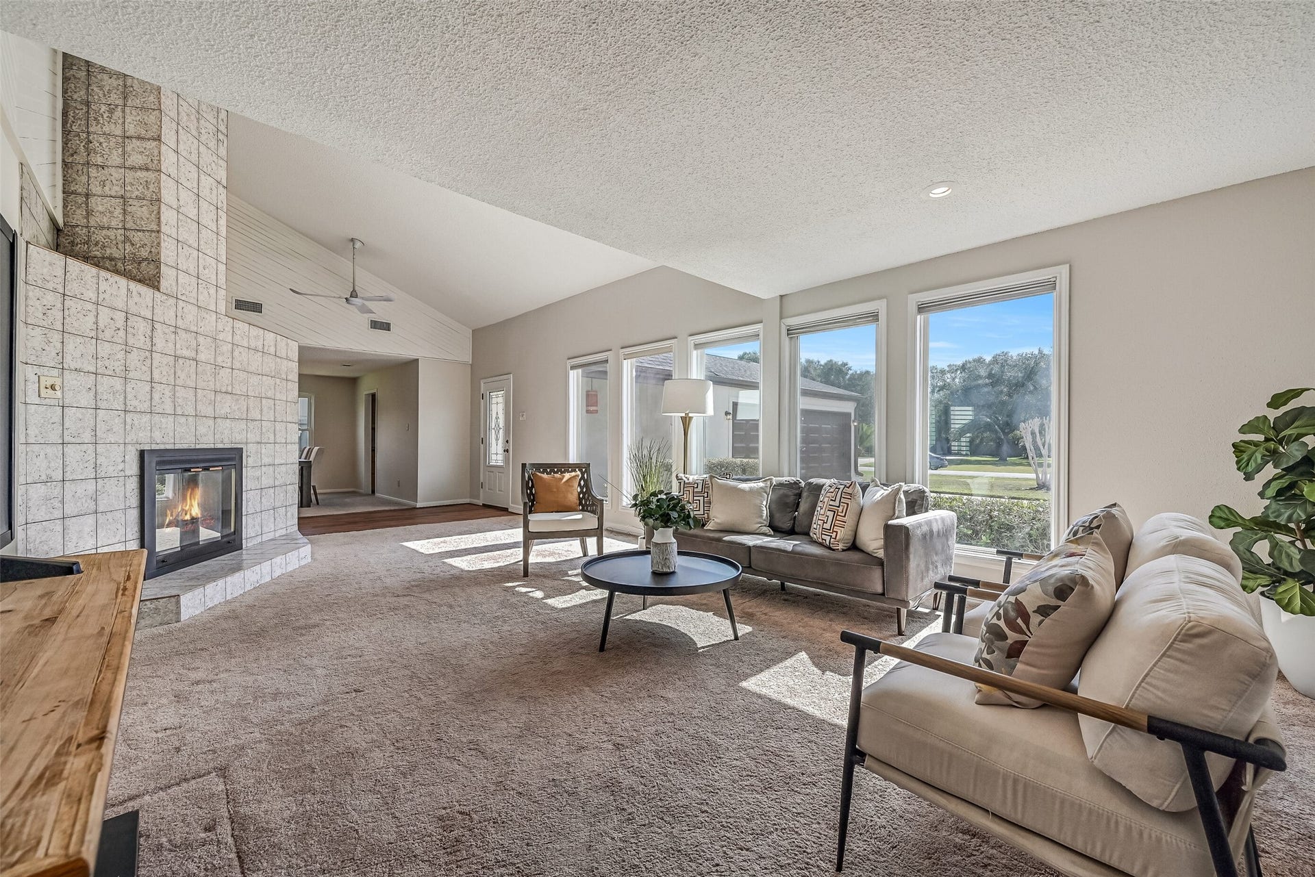 Sunlight pours through a wall of windows into this spacious two-story living room! A dramatic floor-to-ceiling tiled fireplace serves as the focal point, while soaring ceilings, neutral finishes & an upstairs loft overlooking the living area create an open, airy atmosphere.