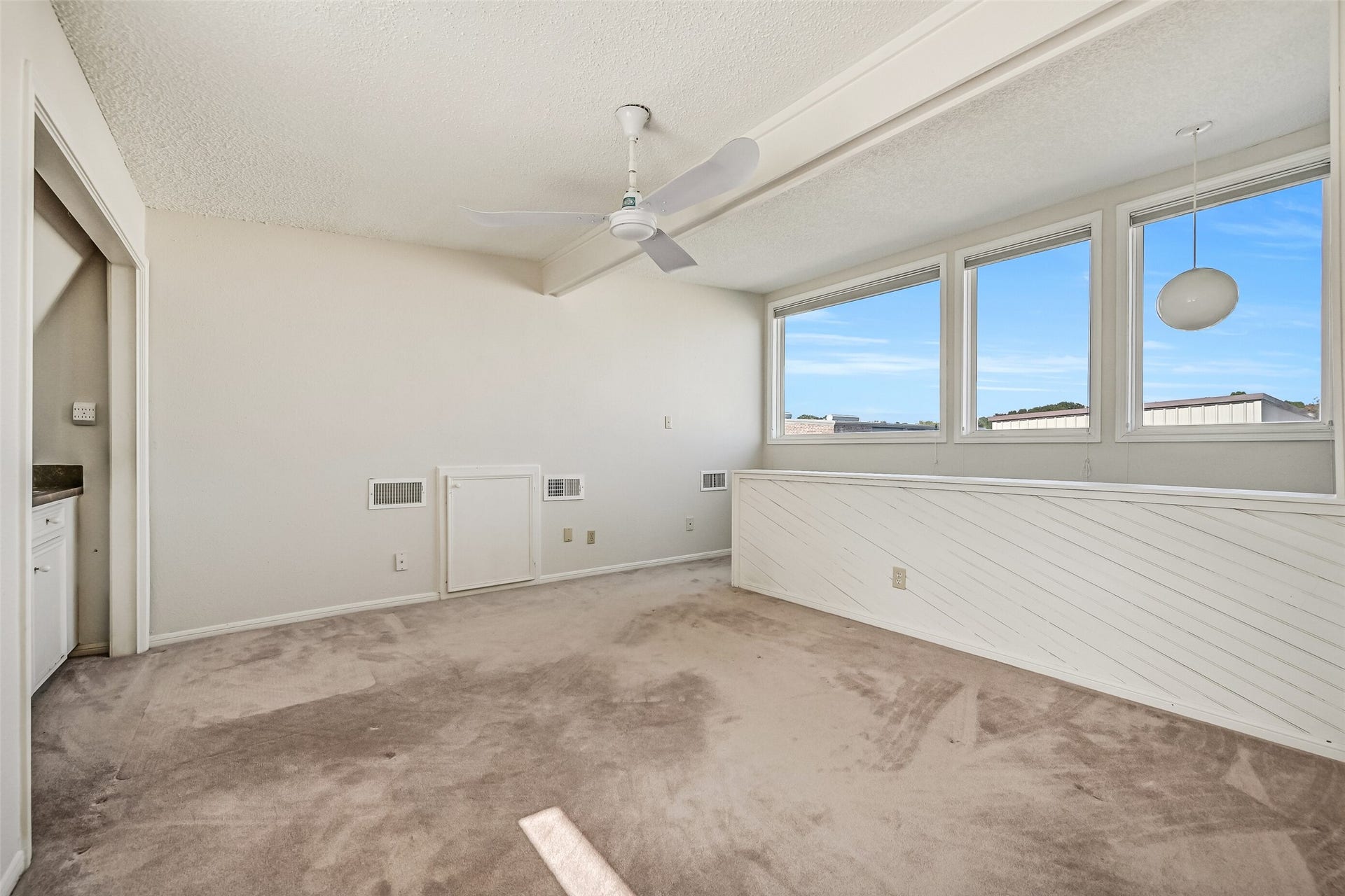 The upstairs loft provides a flexible second living area with neutral carpeting, a ceiling fan & a wall of windows bringing in natural light. Overlooking the two-story living room below, this inviting space is ideal for a game room, media area or home office, with a built-in wet bar nearby.