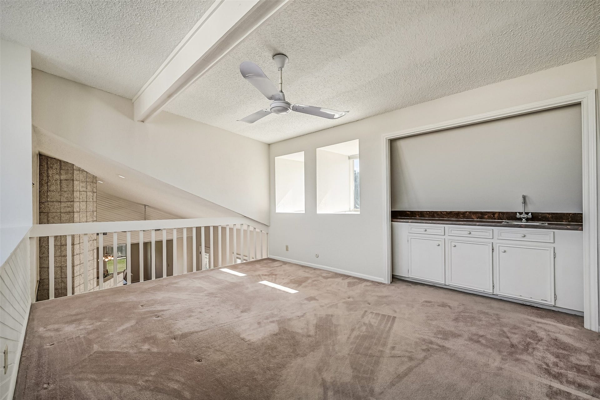 Overlooking the soaring living room and distinctive tiled fireplace, the upstairs loft offers an open, airy setting for entertaining or relaxing. A built-in wet bar with sink, countertop & storage cabinetry adds convenience, while interior openings and windows bring additional natural light into the space.