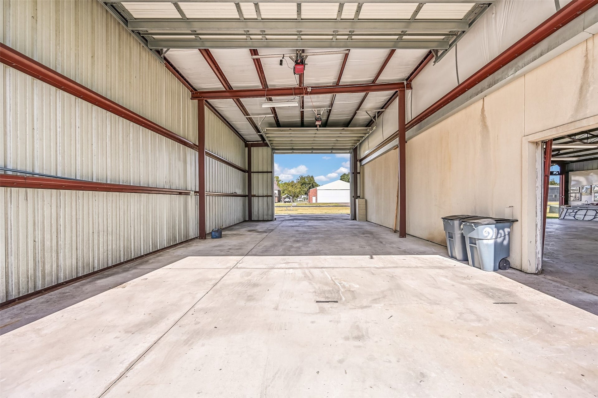 Inside the RV garage, you'll find a spacious open interior with concrete flooring, metal construction, RV power hookup, and overhead doors at both ends for convenient drive-through access. An interior passage connects directly to the adjoining airplane hangar, adding functionality to this impressive outbuilding.
