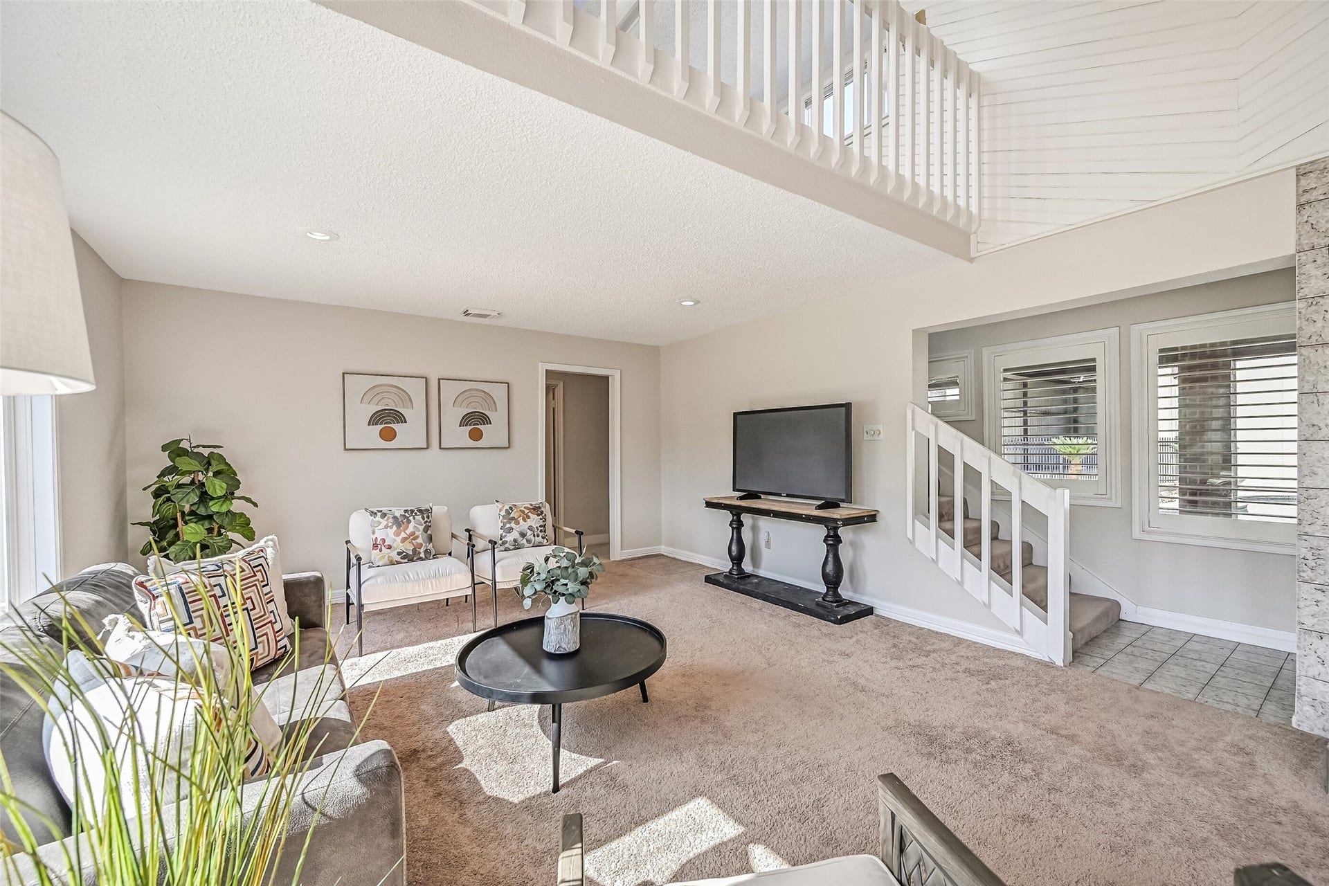 A comfortable seating area beneath the upstairs loft offers plenty of room to relax! Neutral carpeting, recessed lighting & a wall of windows brighten the space, while the staircase provides access to the second-floor loft with its built-in wet bar.
