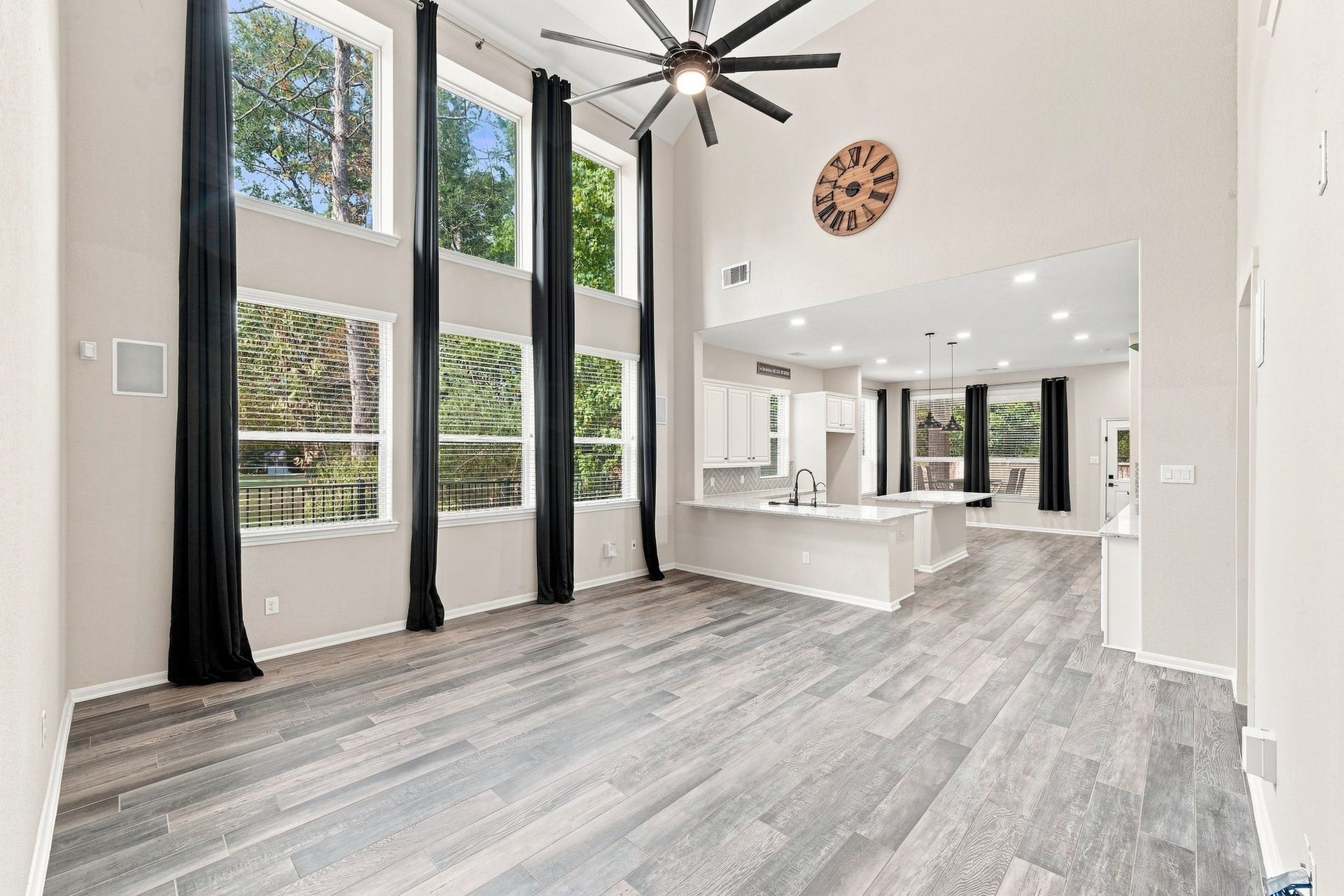 Stunning open-concept living area with soaring ceilings and expansive windows, creating a bright and airy atmosphere. The modern kitchen boasts sleek countertops and an island, perfect for entertaining.