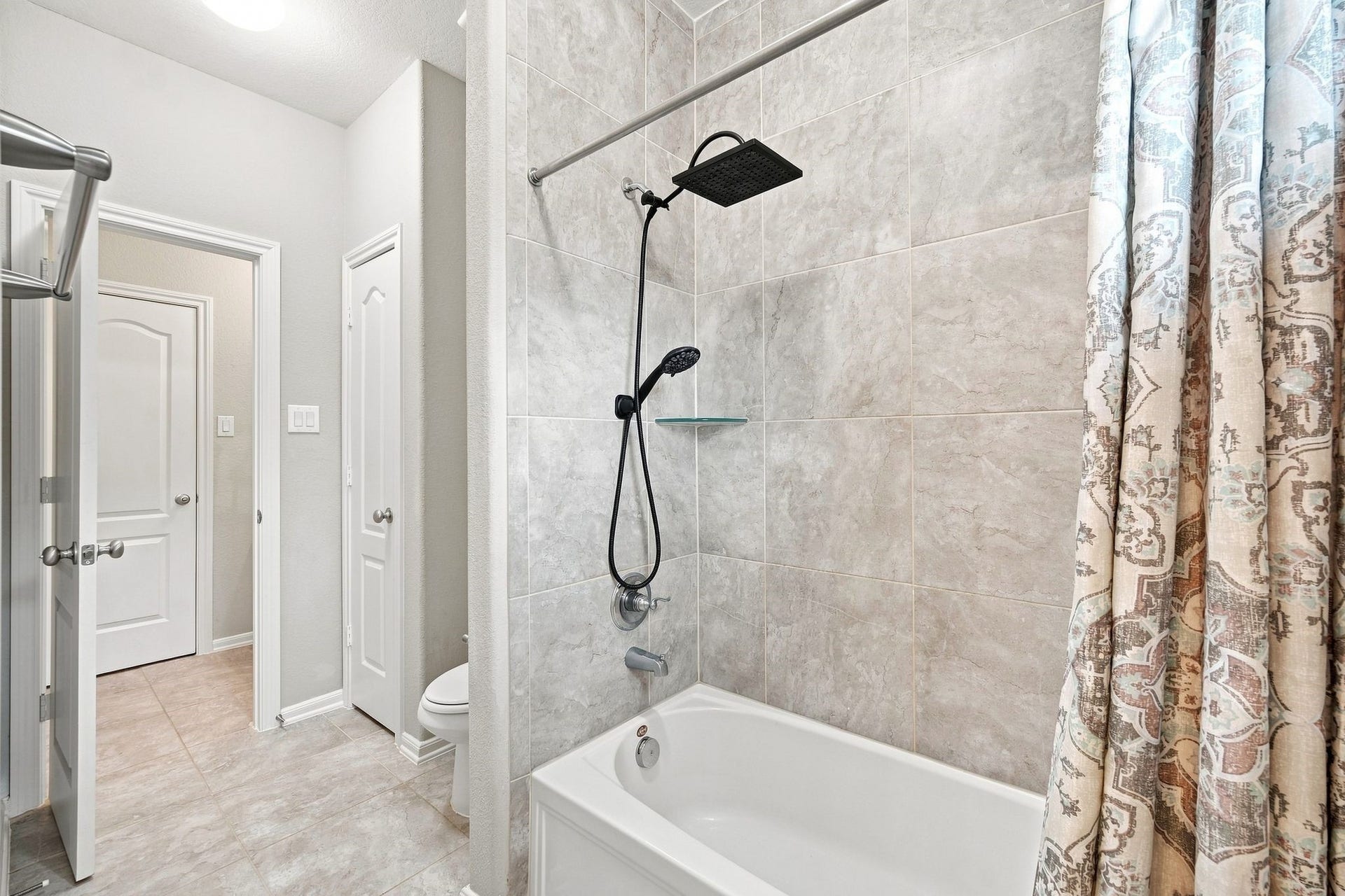 Modern bathroom featuring a sleek shower-tub combo with elegant tile work and a stylish curtain, complemented by neutral tones.