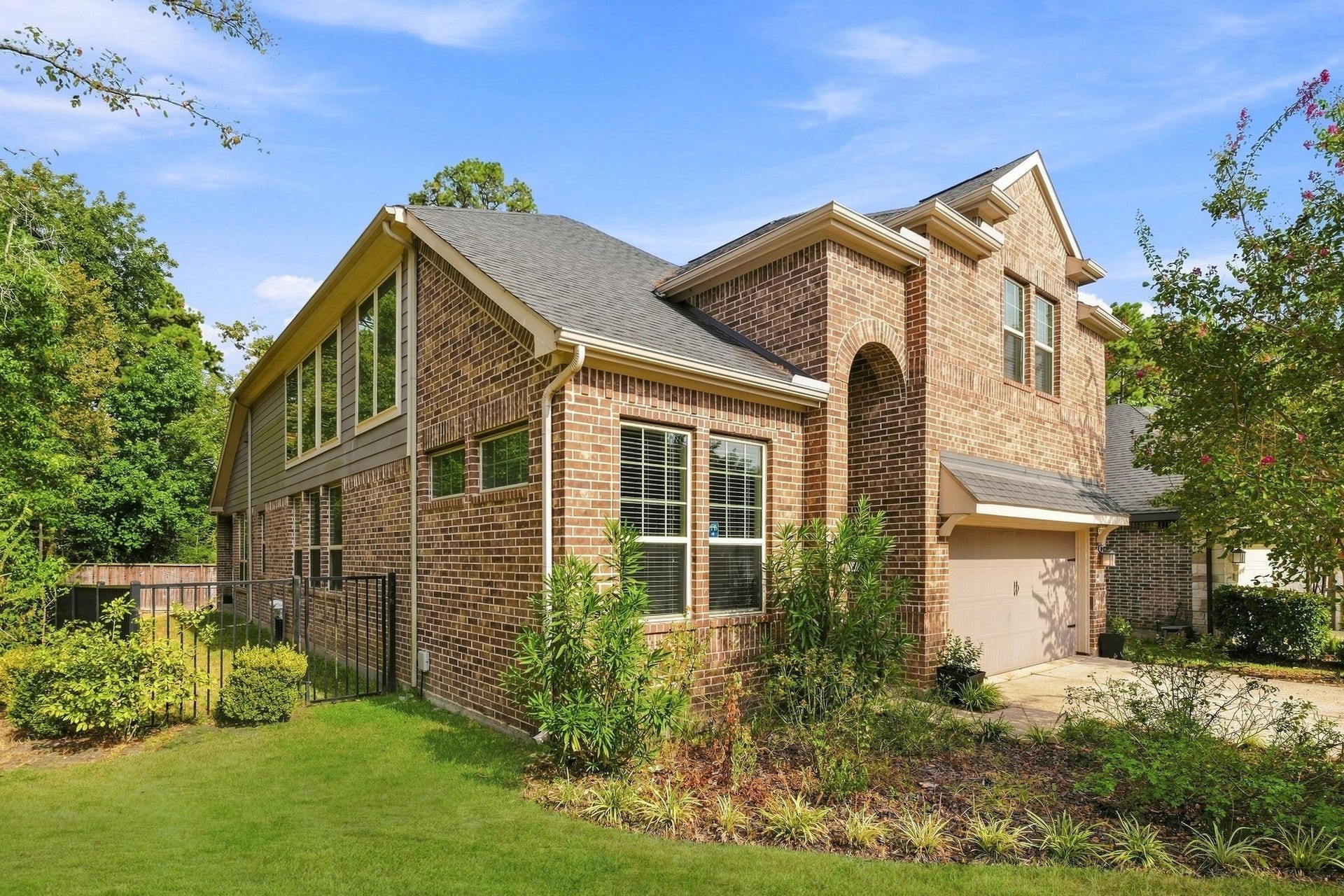 Beautiful brick home with large windows, lush landscaping, and a spacious driveway, offering a blend of elegance and comfort.