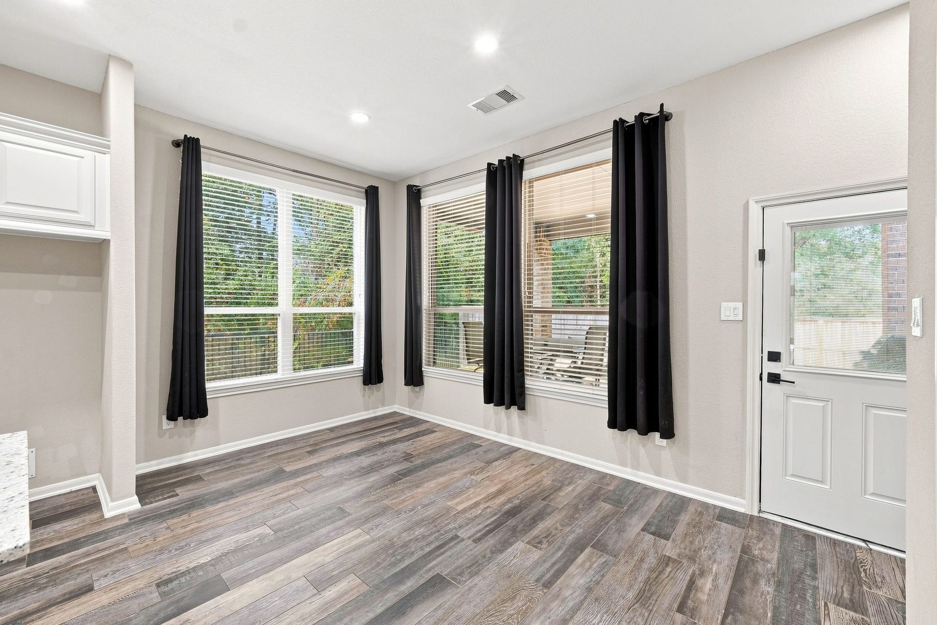 Bright room with large windows, sleek wood flooring, and modern finishes, perfect for a cozy sitting area or home office.