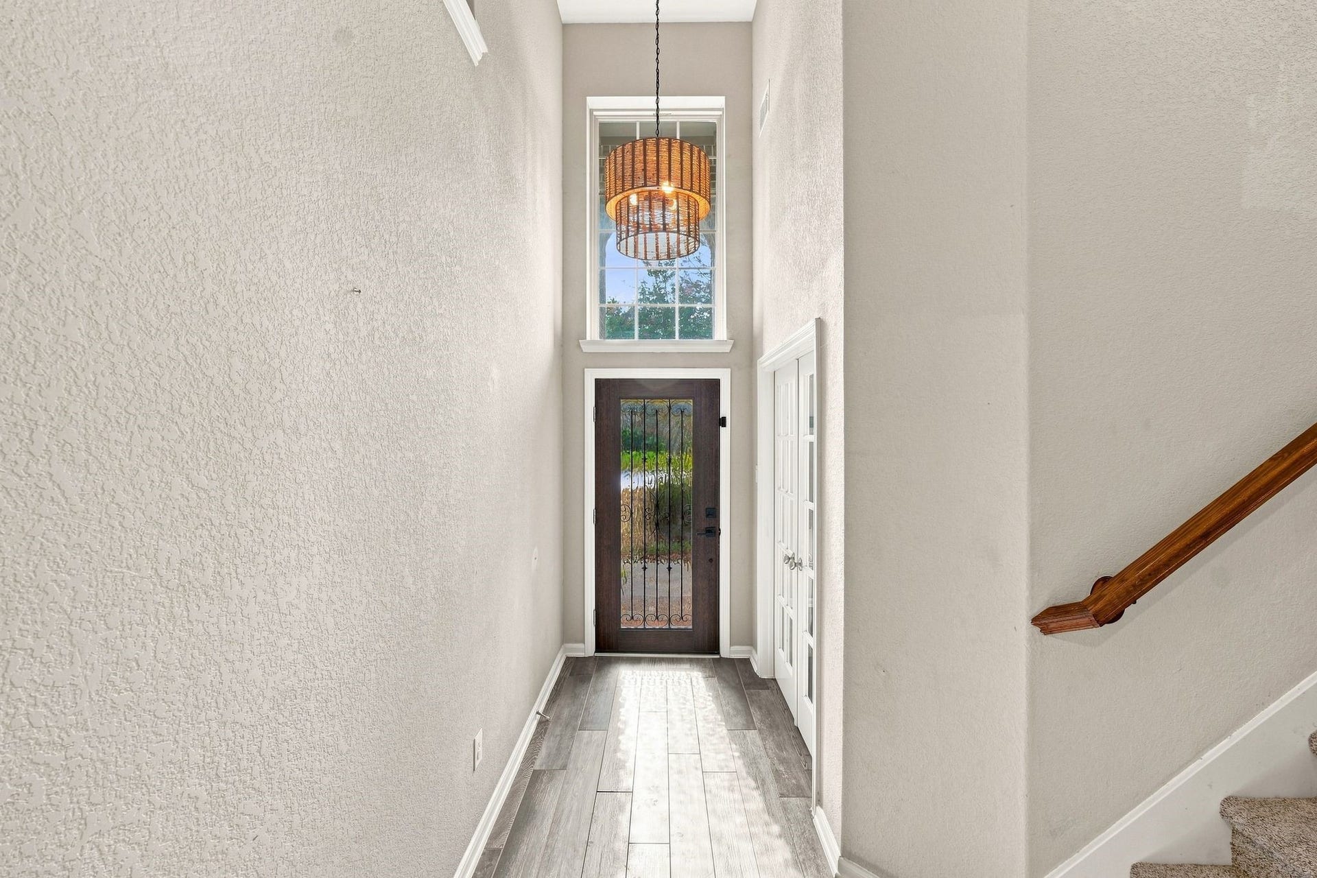 Bright and welcoming entryway featuring a modern chandelier, high ceilings, and a stylish front door with glass panels.