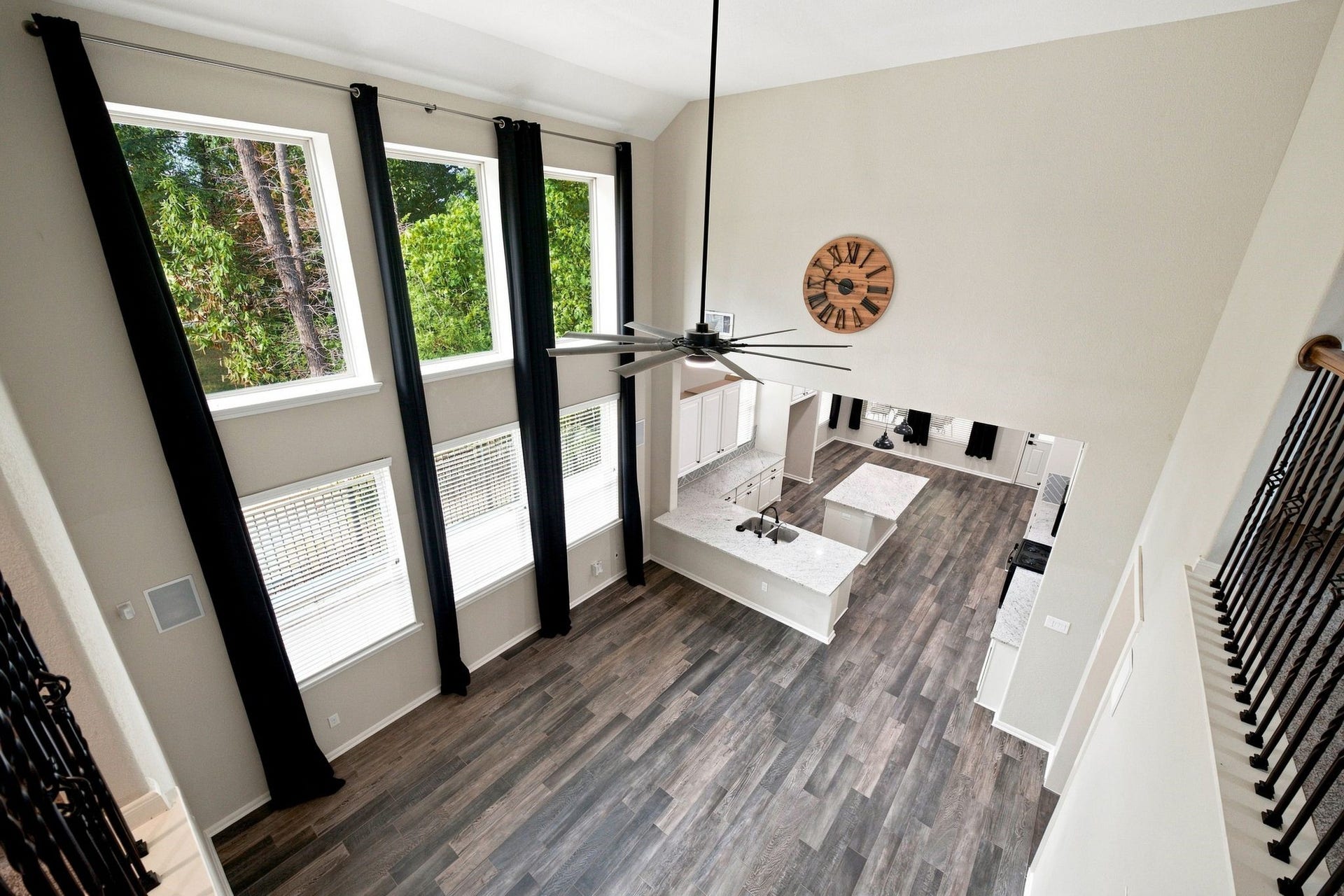 Stunning open-concept living space with soaring ceilings, abundant natural light from oversized windows, and elegant dark wood flooring.