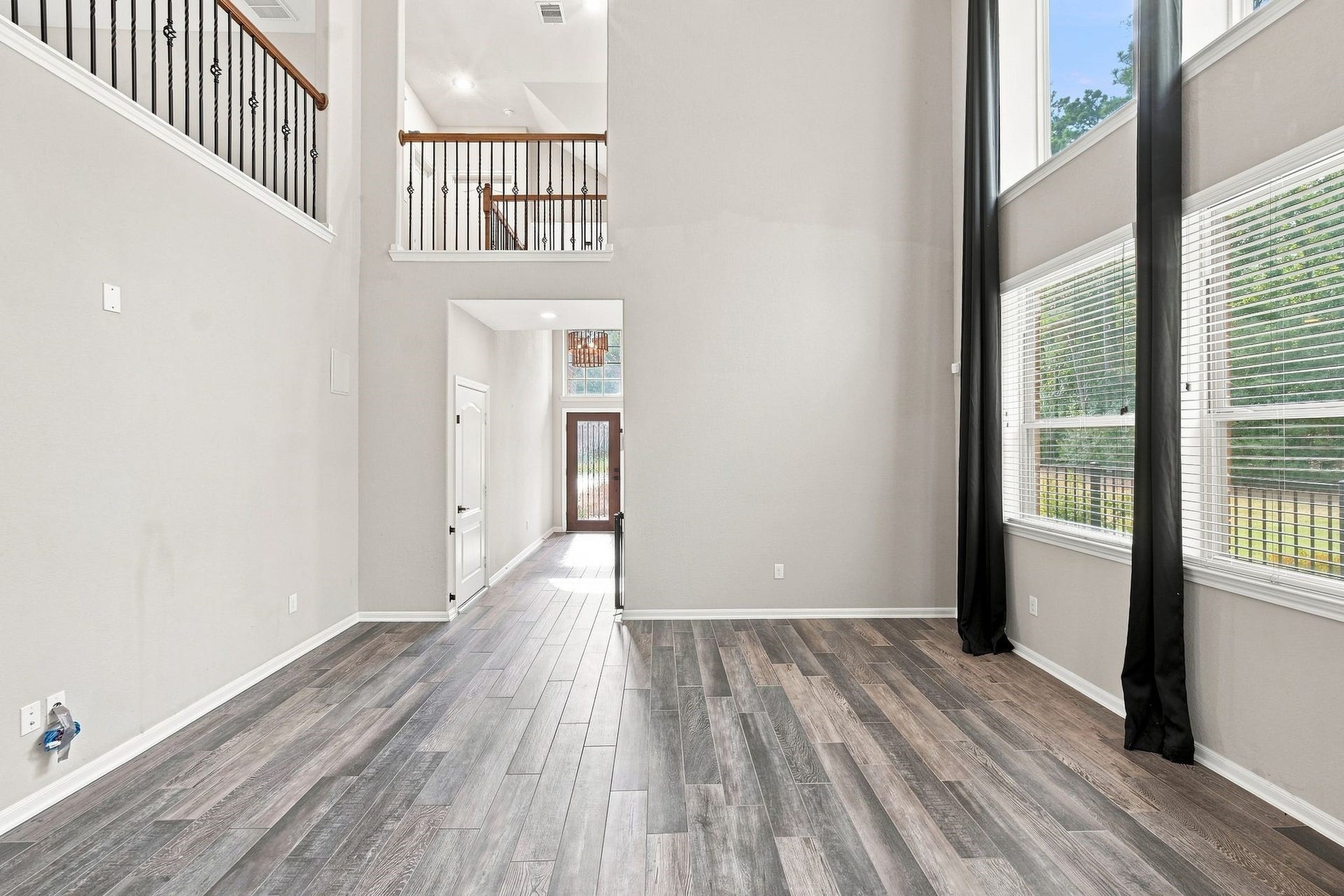 Stunning double-height living area with expansive windows, sleek wood flooring, and a view to the upper level, creating a bright and airy ambiance.