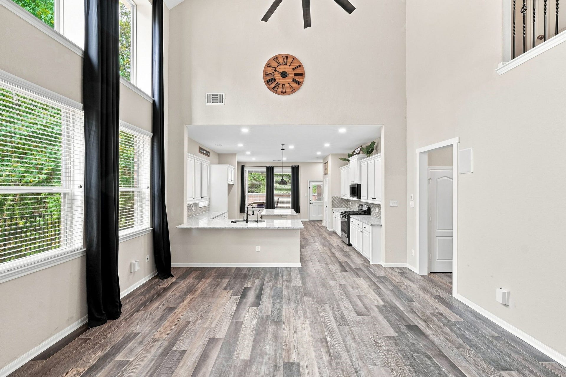 Stunning open-concept living area with soaring ceilings, expansive windows for natural light, and a modern kitchen featuring sleek countertops and contemporary cabinetry.