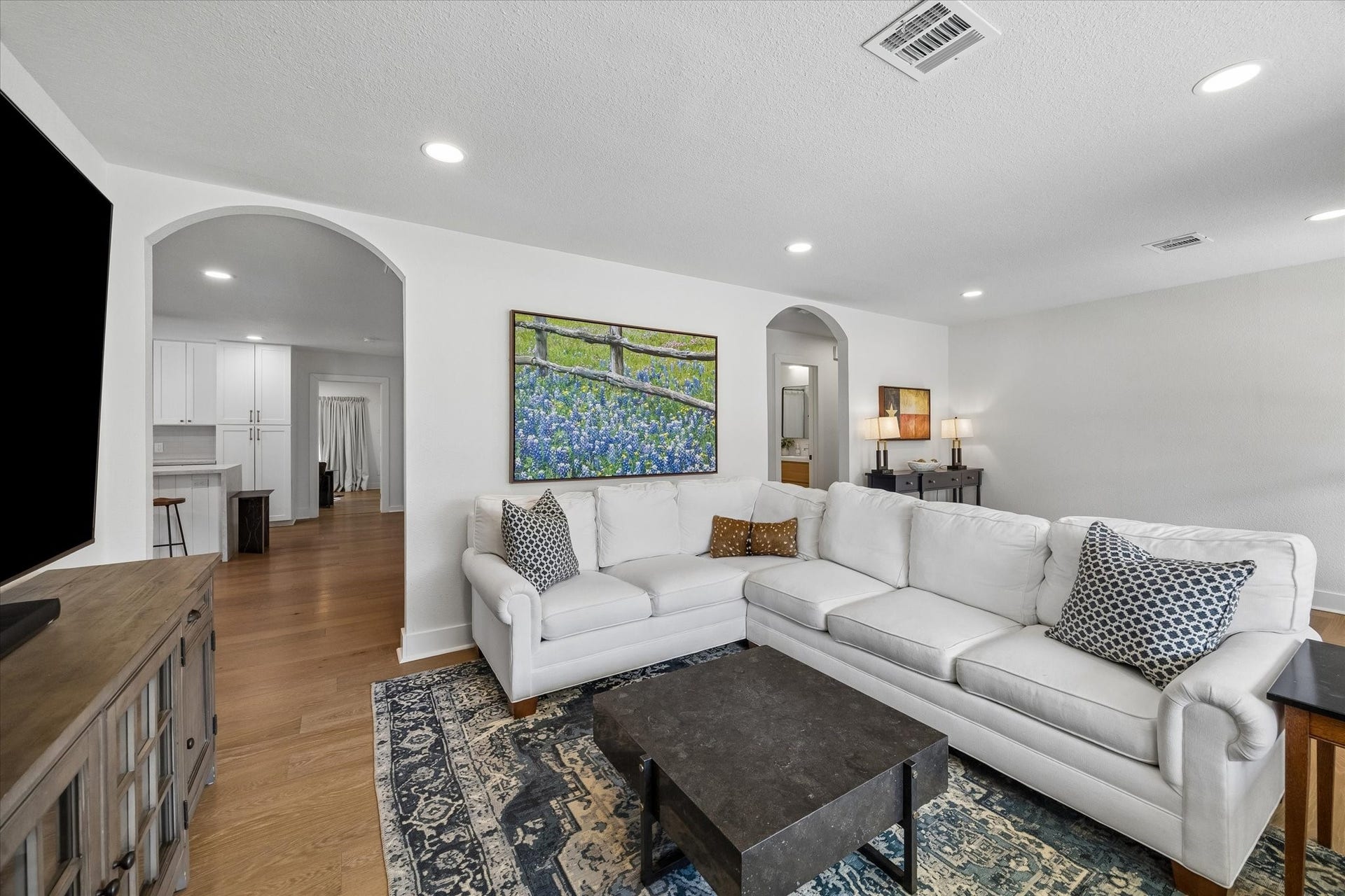 Thoughtful sightlines connect the living room to the kitchen while still giving each space its own definition. Wide arched openings add architectural character to the open layout.