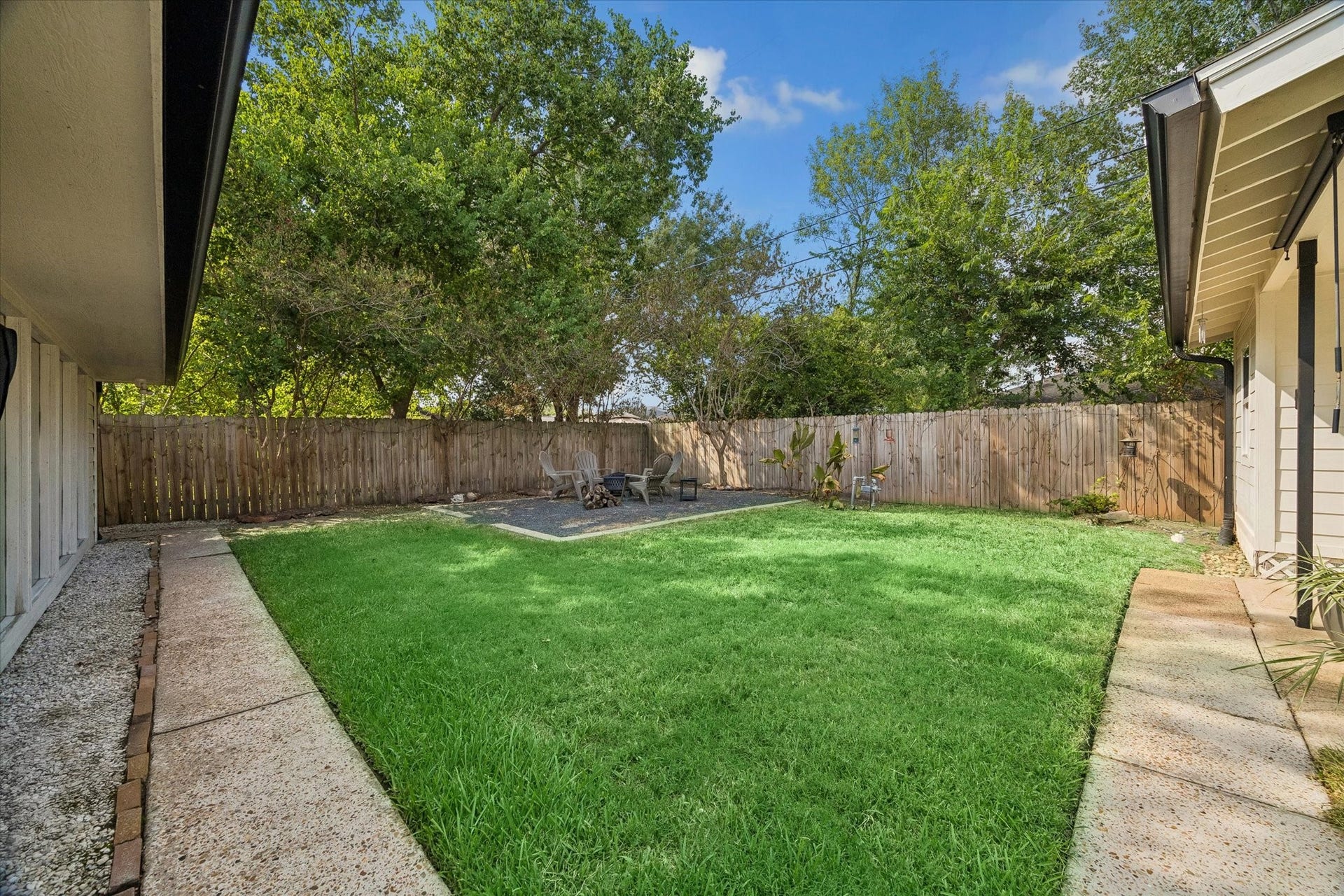 A spacious backyard creates plenty of room to play, entertain, or unwind, with a dedicated fire pit area tucked beneath mature trees for evenings outdoors.