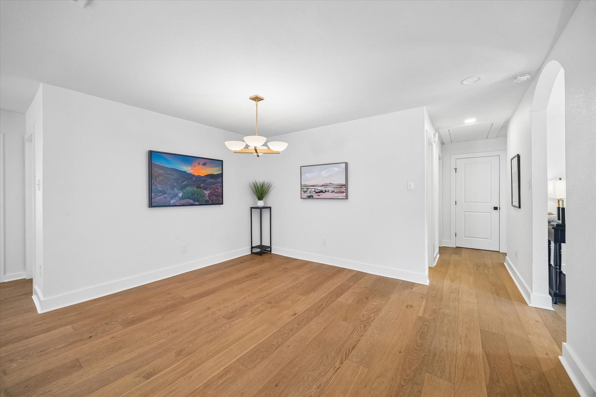 Warm wood flooring and a sculptural statement light give the formal dining room a polished feel, with an open connection to the main living spaces that makes hosting flow naturally.