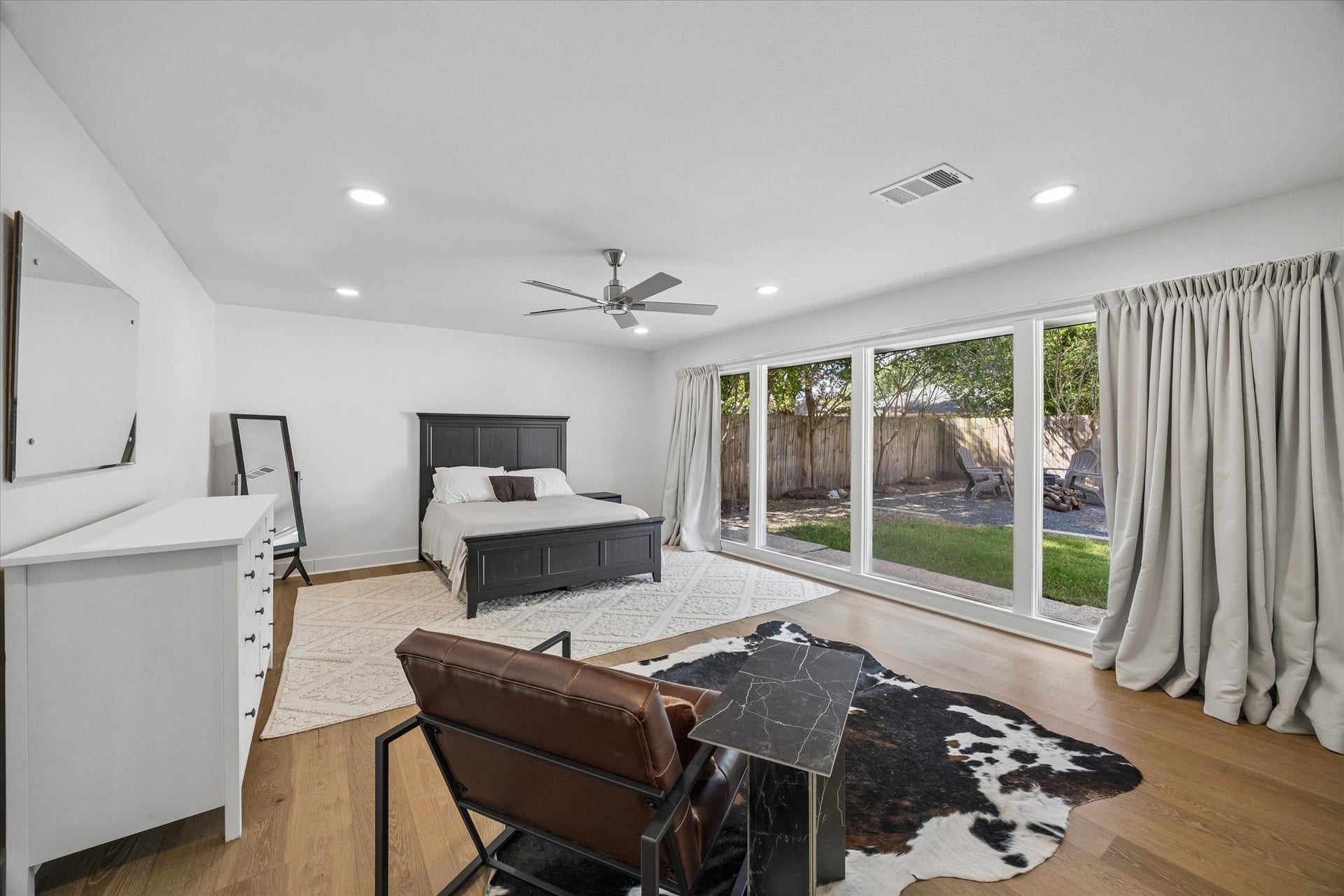 An impressive wall of windows stretches across the primary suite, filling the oversized retreat with natural light while framing views of the backyard.