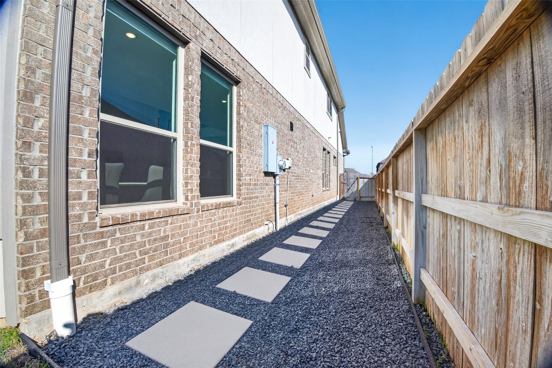 1315 Munson Valley Road, Richmond, TX 77406 Low-maintenance side yard offers a practical and visually appealing design with decorative dark gravel, concrete pavers, and privacy fencing.
