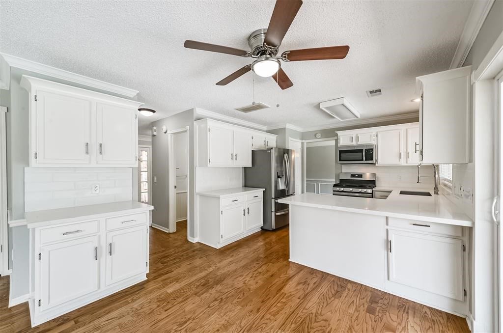 Indulge in the art of culinary creation in this spacious kitchen, adorned with pristine white cabinets, offering both functionality and timeless elegance. Your culinary masterpiece begins here
