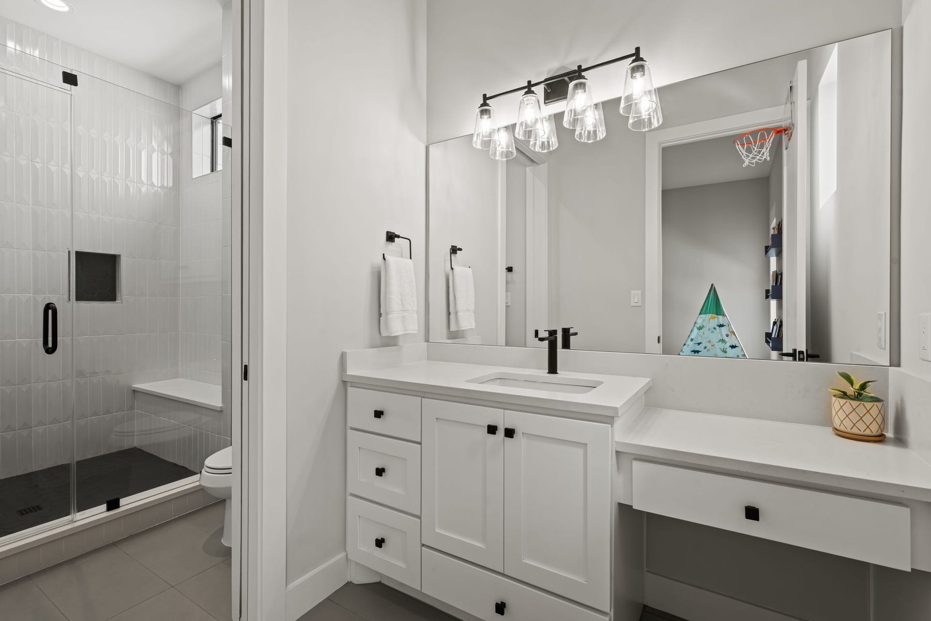 733 E 10th 1/2 Street, Houston, TX 77008 An en-suite bath combines a quartz-topped vanity with crisp tilework and modern hardware. The thoughtful layout provides privacy and convenience for the adjoining bedroom.