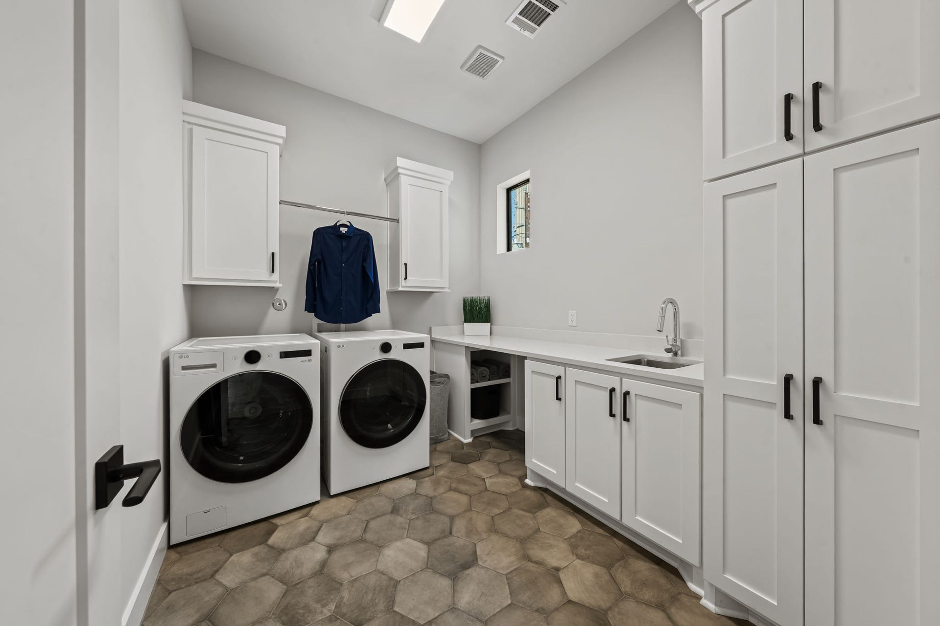 733 E 10th 1/2 Street, Houston, TX 77008 The second-floor utility room is designed with a sink, hanging rod, built-in storage, and patterned hex tile. Gas and electric dryer connections offer added flexibility.