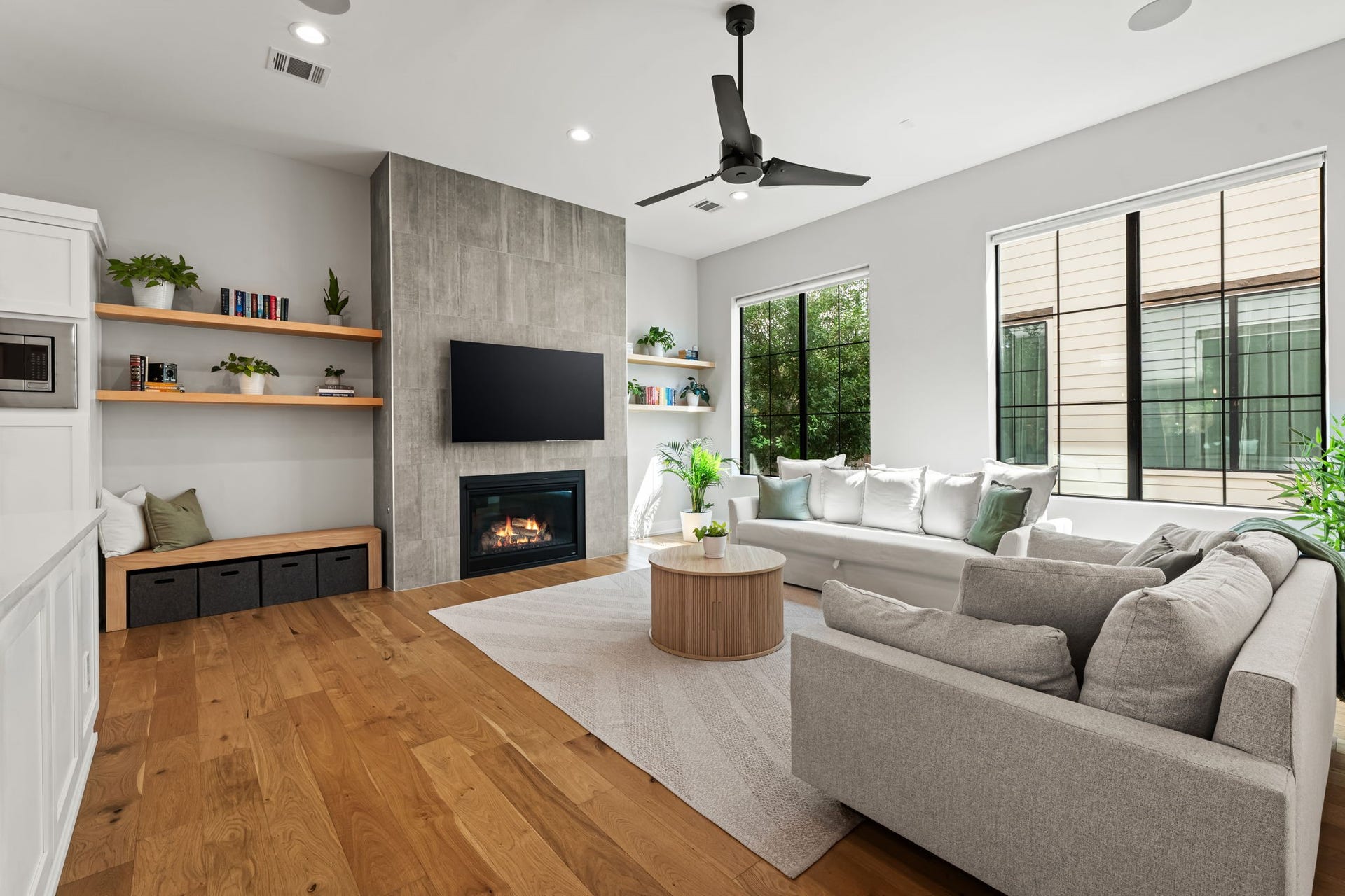 733 E 10th 1/2 Street, Houston, TX 77008 The light-filled living room centers on a gas-log fireplace with a dramatic floor-to-ceiling tile surround. Wide-plank white oak flooring and built-in speakers create an elegant setting for relaxed gatherings.