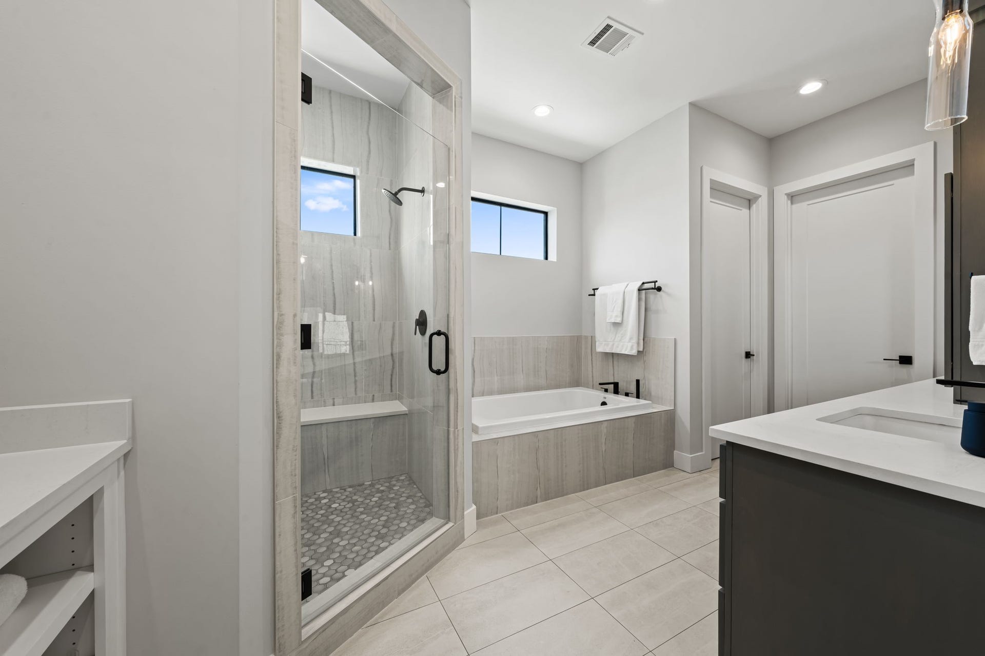 733 E 10th 1/2 Street, Houston, TX 77008 The primary bath's oversized shower features dual showerheads, integrated niches, and refined tilework. A glass enclosure preserves the room's bright and open presentation.