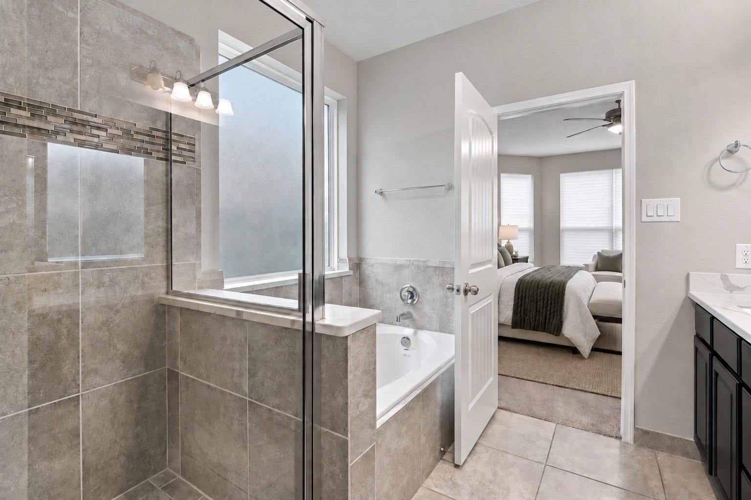 24115 Lake Molveno Drive, Katy, TX 77493 This luxurious primary ensuite features a dual-amenity setup with a glass-enclosed walk-in shower and a deep soaking tub. Elegant tile work extends across the shower walls and tub surround, complemented by a large privacy-glass window.