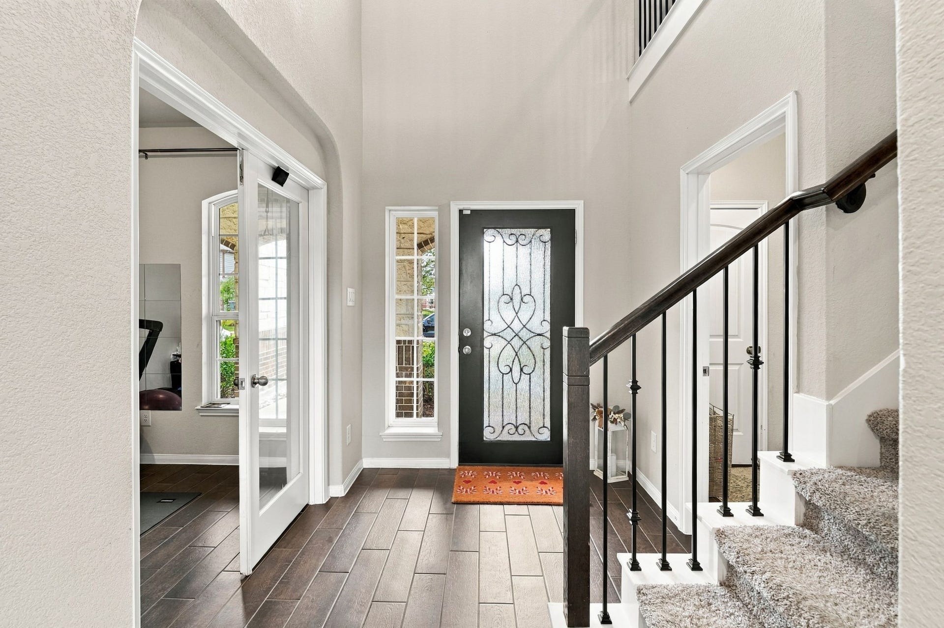 24115 Lake Molveno Drive, Katy, TX 77493 Built to impress, this entryway combines dramatic architectural heights with a clean, functional floor plan. Rich wood-look flooring leads past a staircase accented with decorative iron spindles.