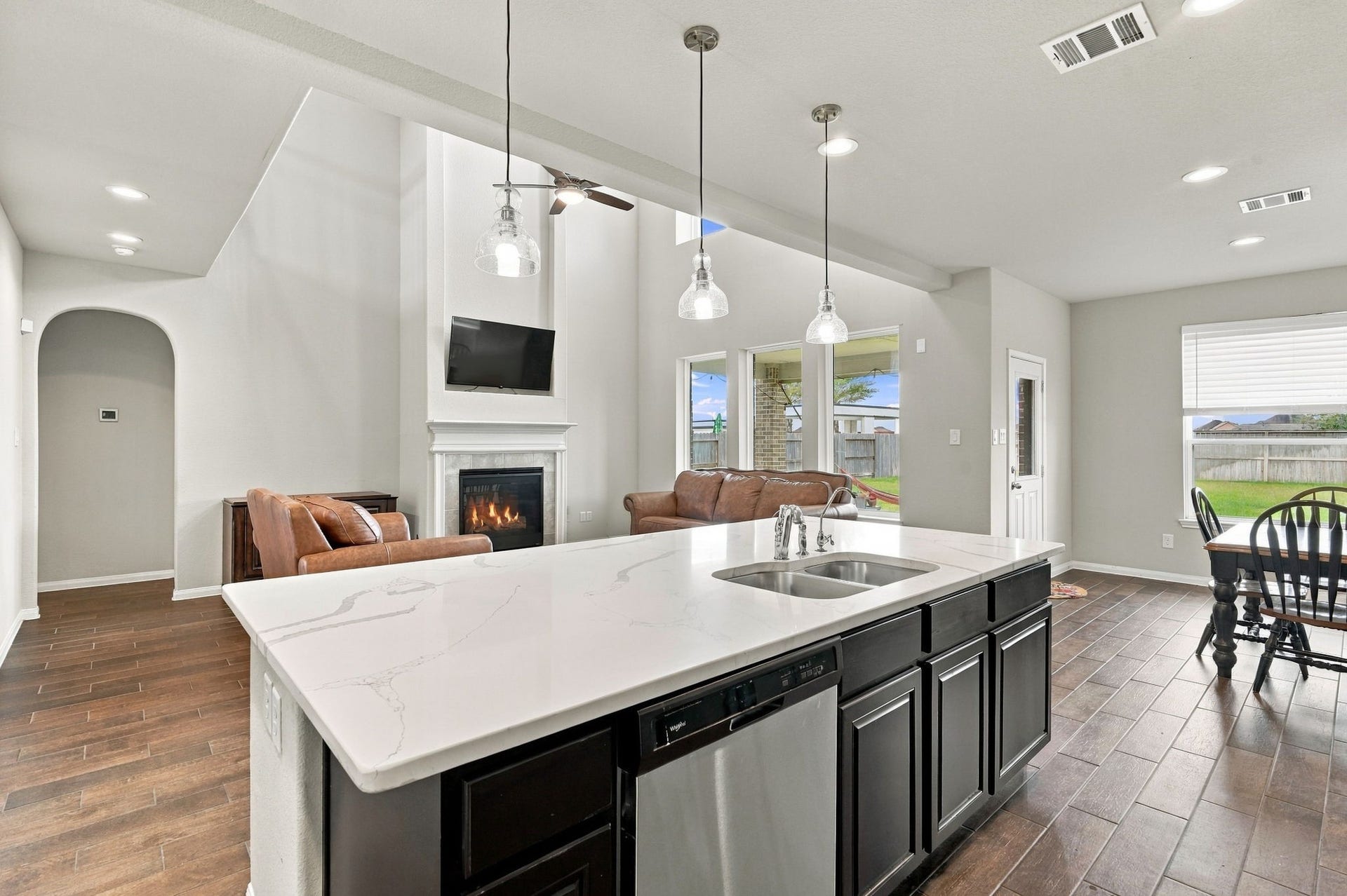 24115 Lake Molveno Drive, Katy, TX 77493 Virtually Staged: Looking out from behind the expansive kitchen island, this view highlights the seamless layout connecting the kitchen, two-story living room, and sunlit dining area.