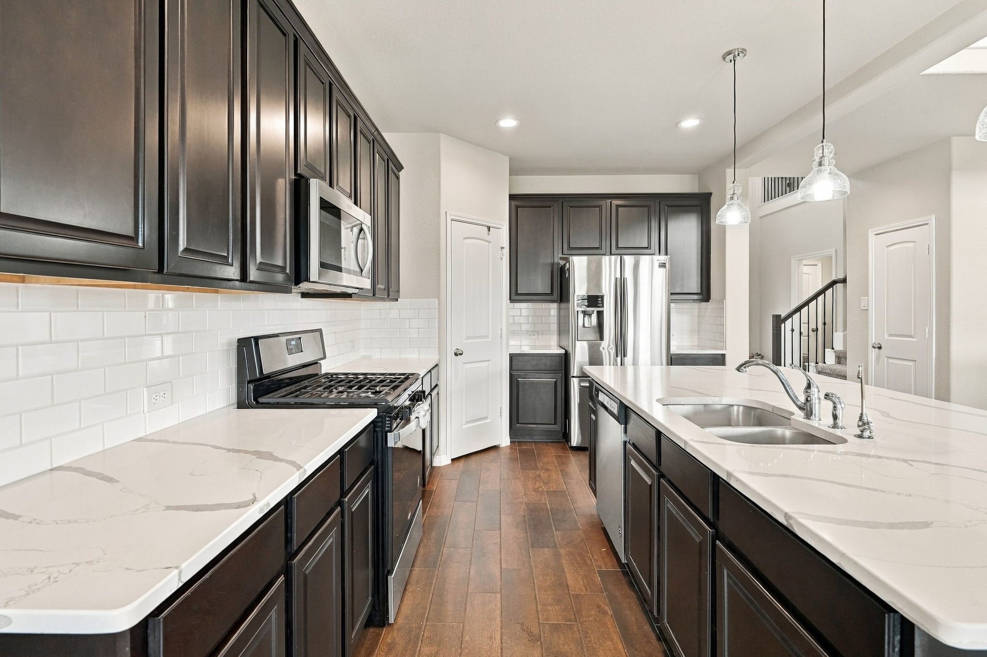 24115 Lake Molveno Drive, Katy, TX 77493 Rich, dark cabinetry lining both sides provides exceptional storage capacity, while a large center island offers extensive prep space.
