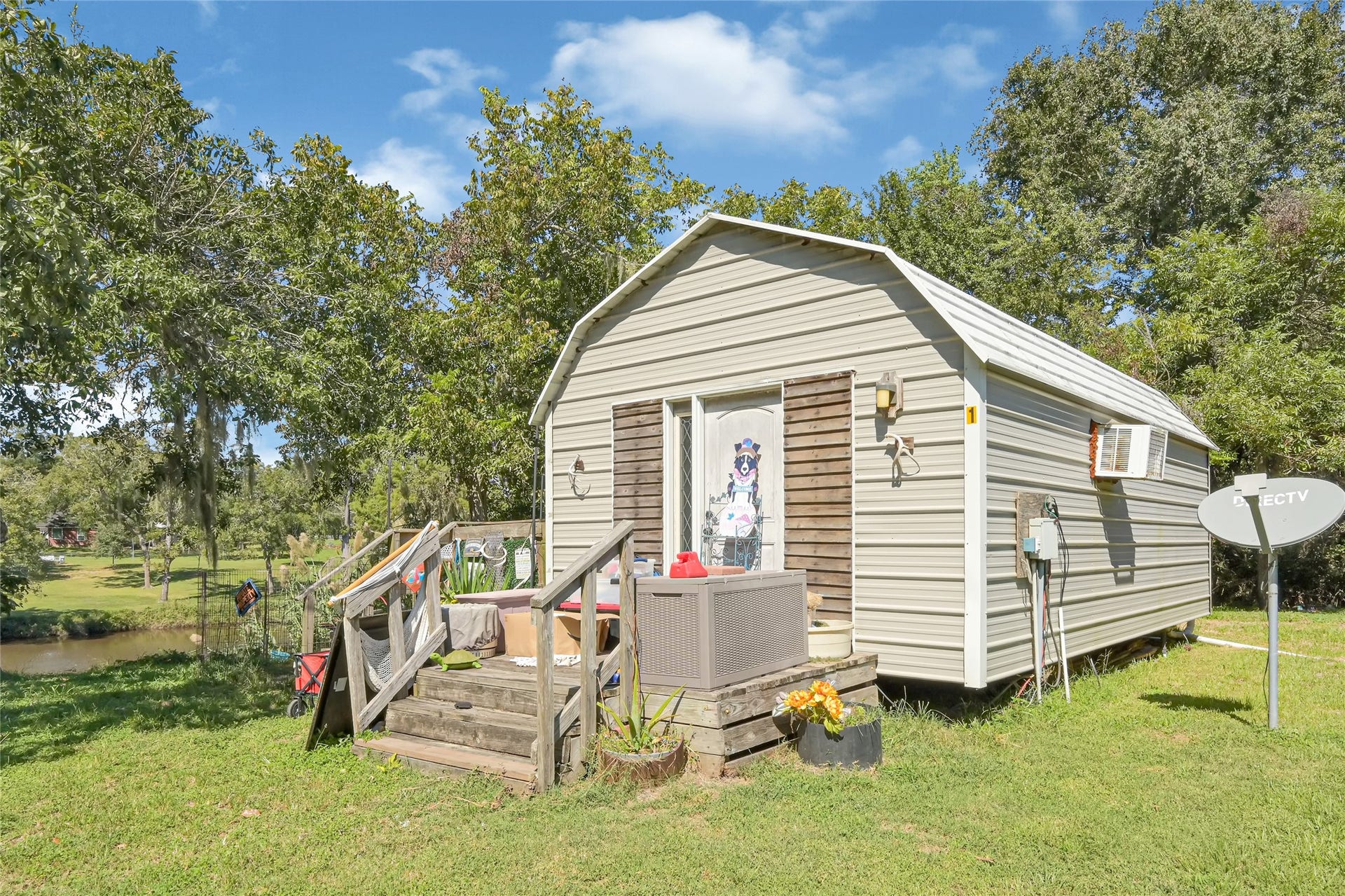 121 Patterson Road, #CR814, Brazoria, TX 77422 Charming small cabin nestled in lush greenery, offering a cozy retreat with a picturesque view of a nearby stream.