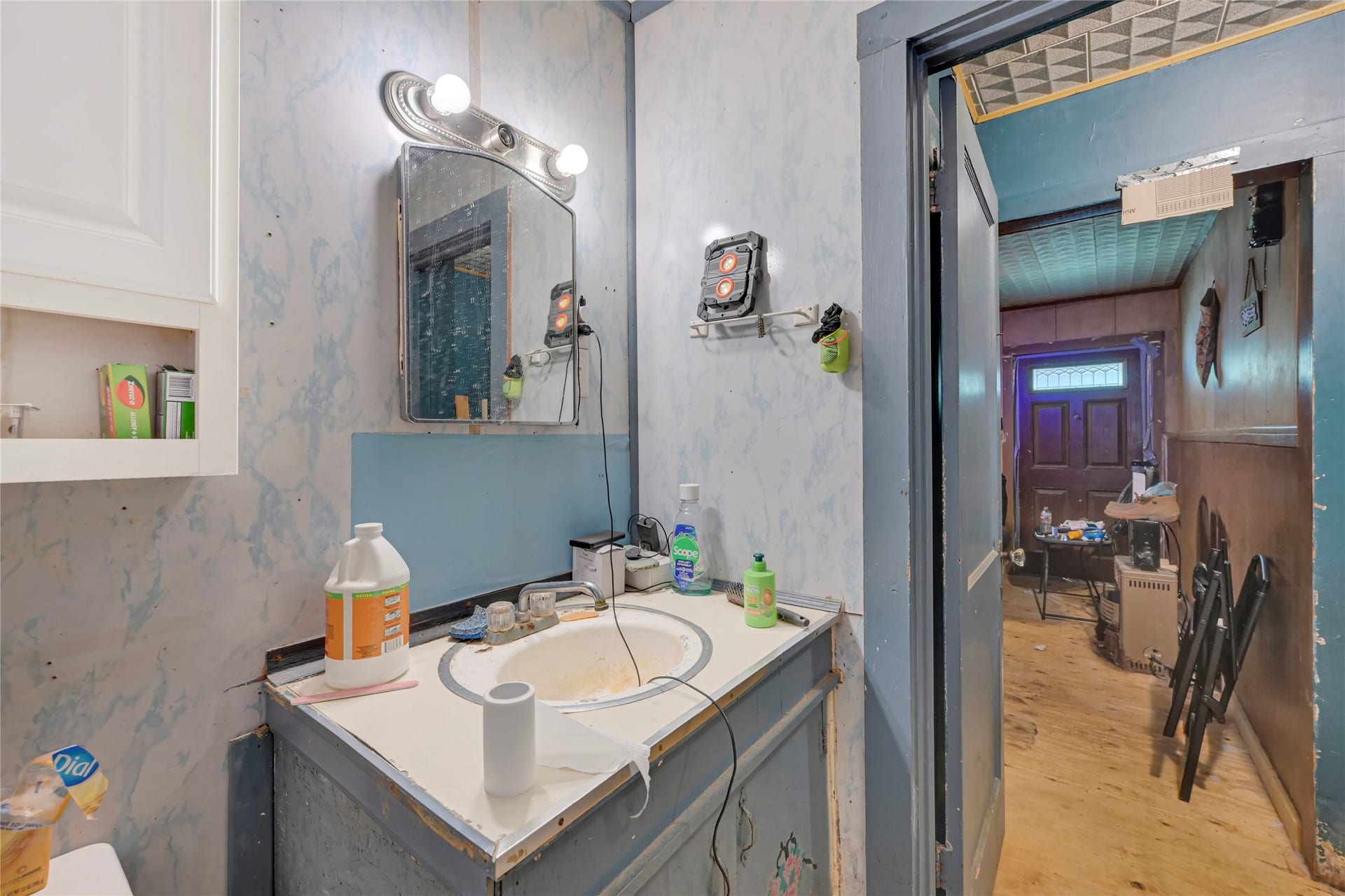 121 Patterson Road, #CR814, Brazoria, TX 77422 Cozy bathroom with a vintage vibe features a large mirror, ample lighting, and classic cabinetry, leading into a rustic hallway.