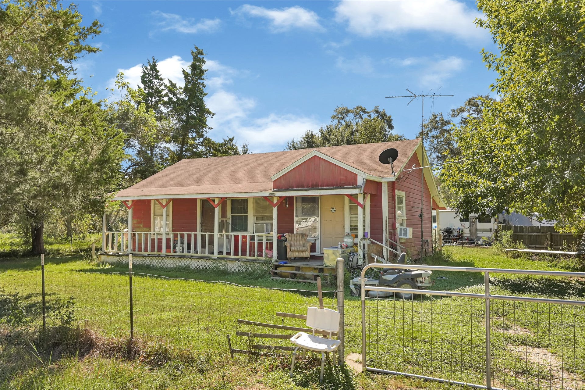 121 Patterson Road, #CR814, Brazoria, TX 77422 Charming country home with a welcoming front porch, nestled amid mature trees and lush greenery, perfect for enjoying serene outdoor moments.
