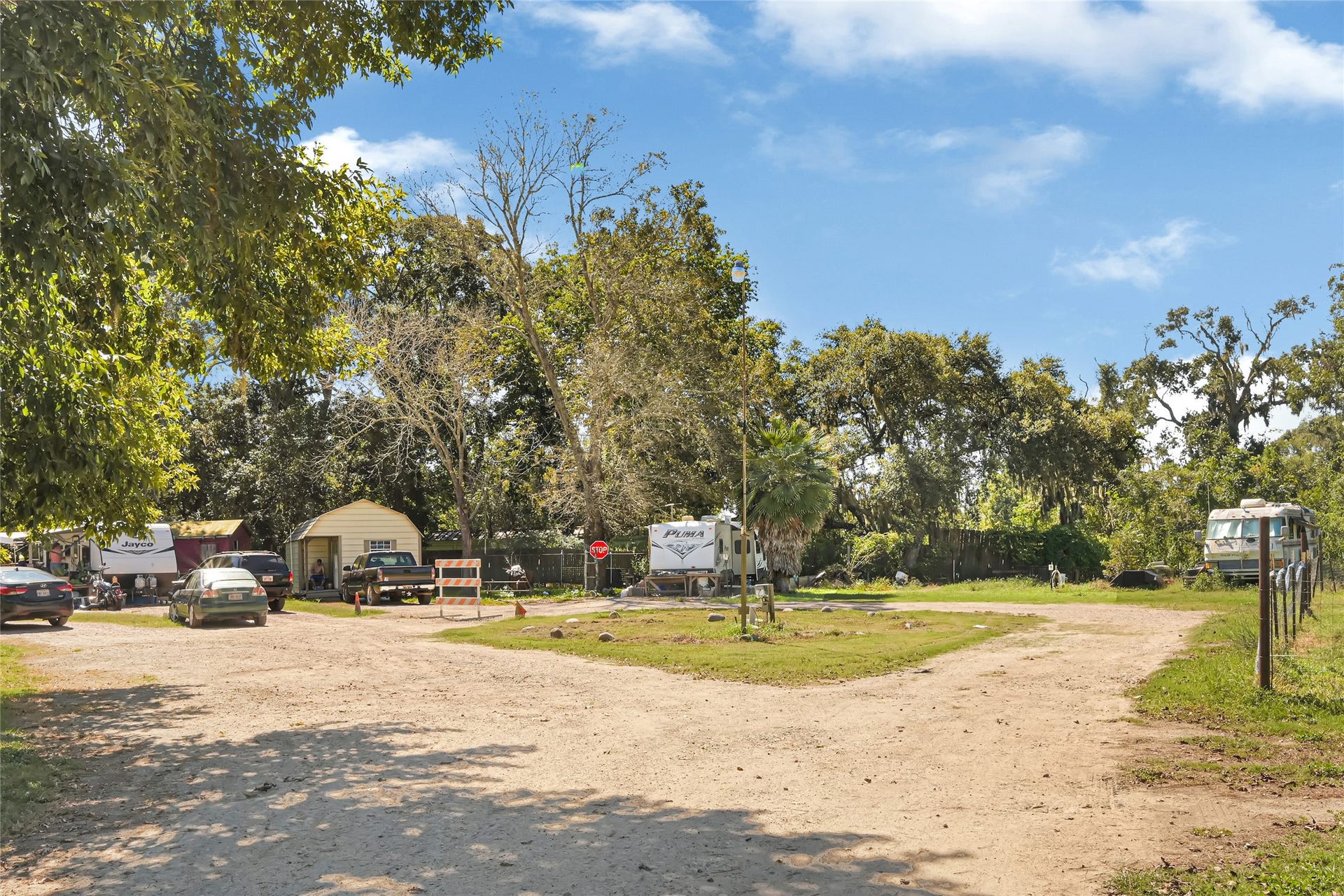 121 Patterson Road, #CR814, Brazoria, TX 77422 Spacious outdoor area with mature trees, multiple vehicles, and RVs, offering a rustic setting ideal for flexible living arrangements.