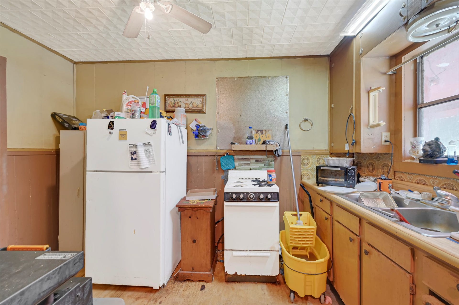 121 Patterson Road, #CR814, Brazoria, TX 77422 Cozy kitchen space featuring vintage cabinetry, ample storage, and natural light from a large window, offering a charming opportunity for customization and renovation.